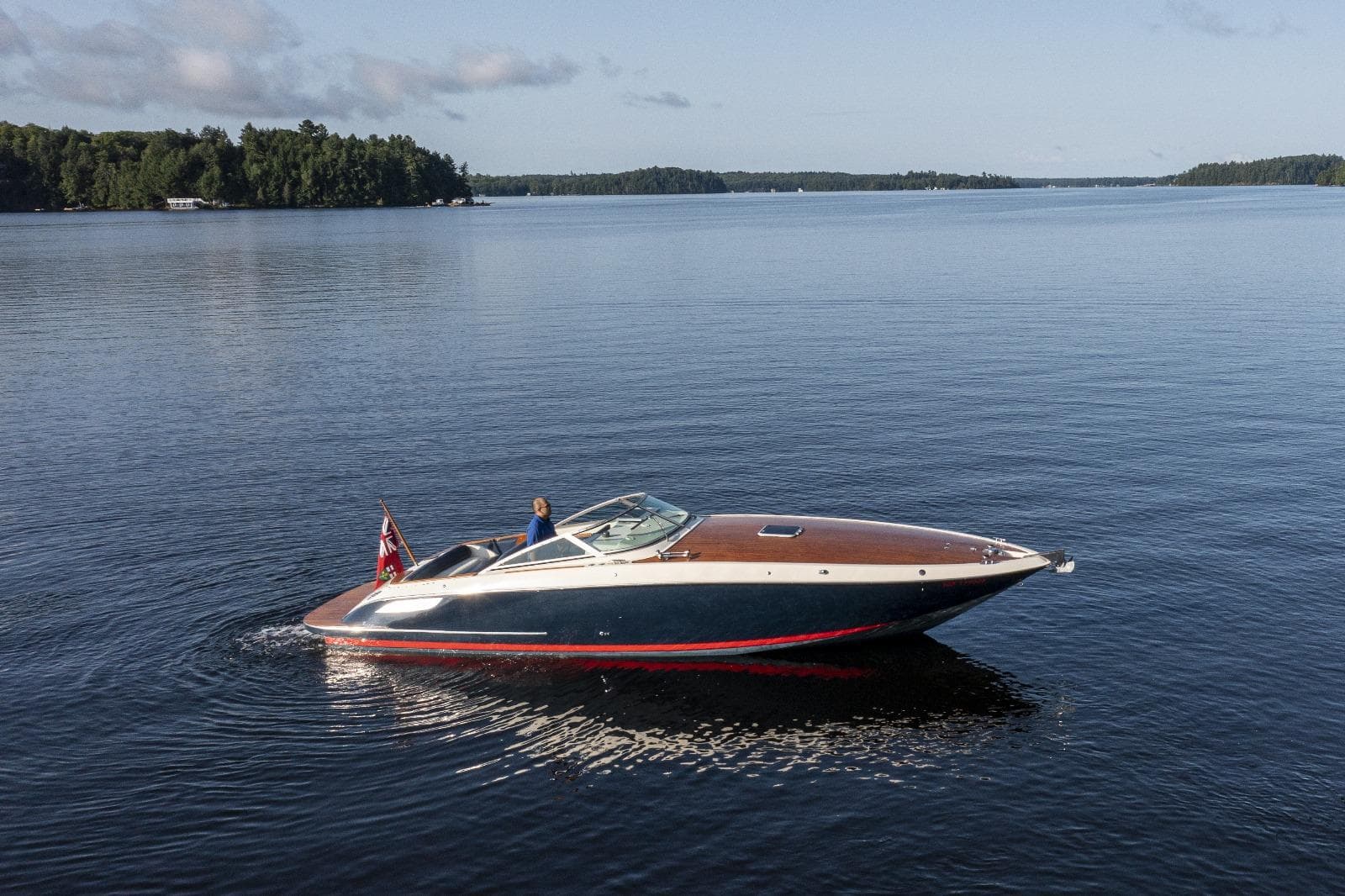 A 1997 Kavalk 30 boat cruising on a calm lake under a clear sky.