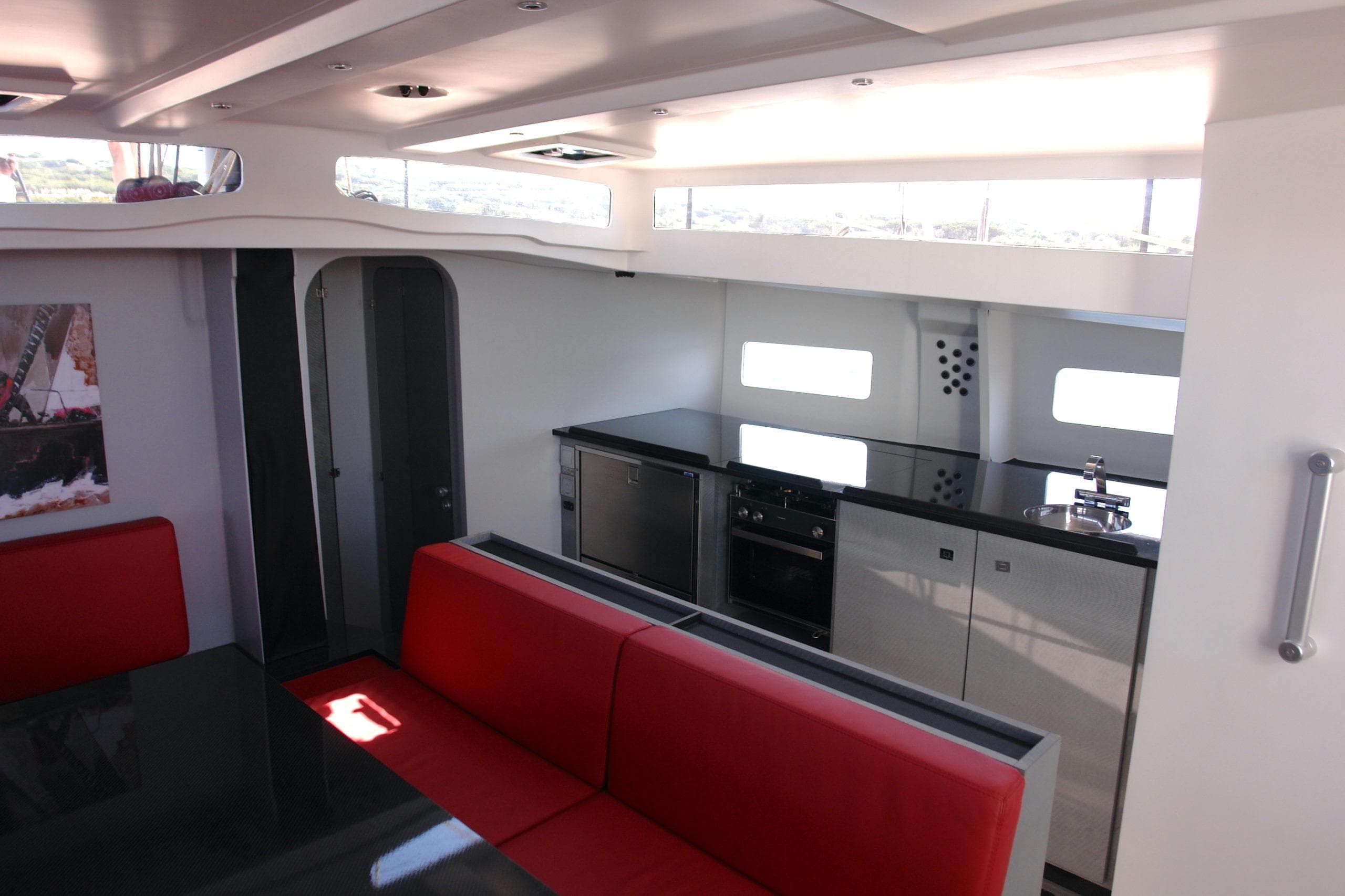 Modern yacht interior with red seating, sleek kitchen, and ample natural light, Black Pepper Code 2, 2025.