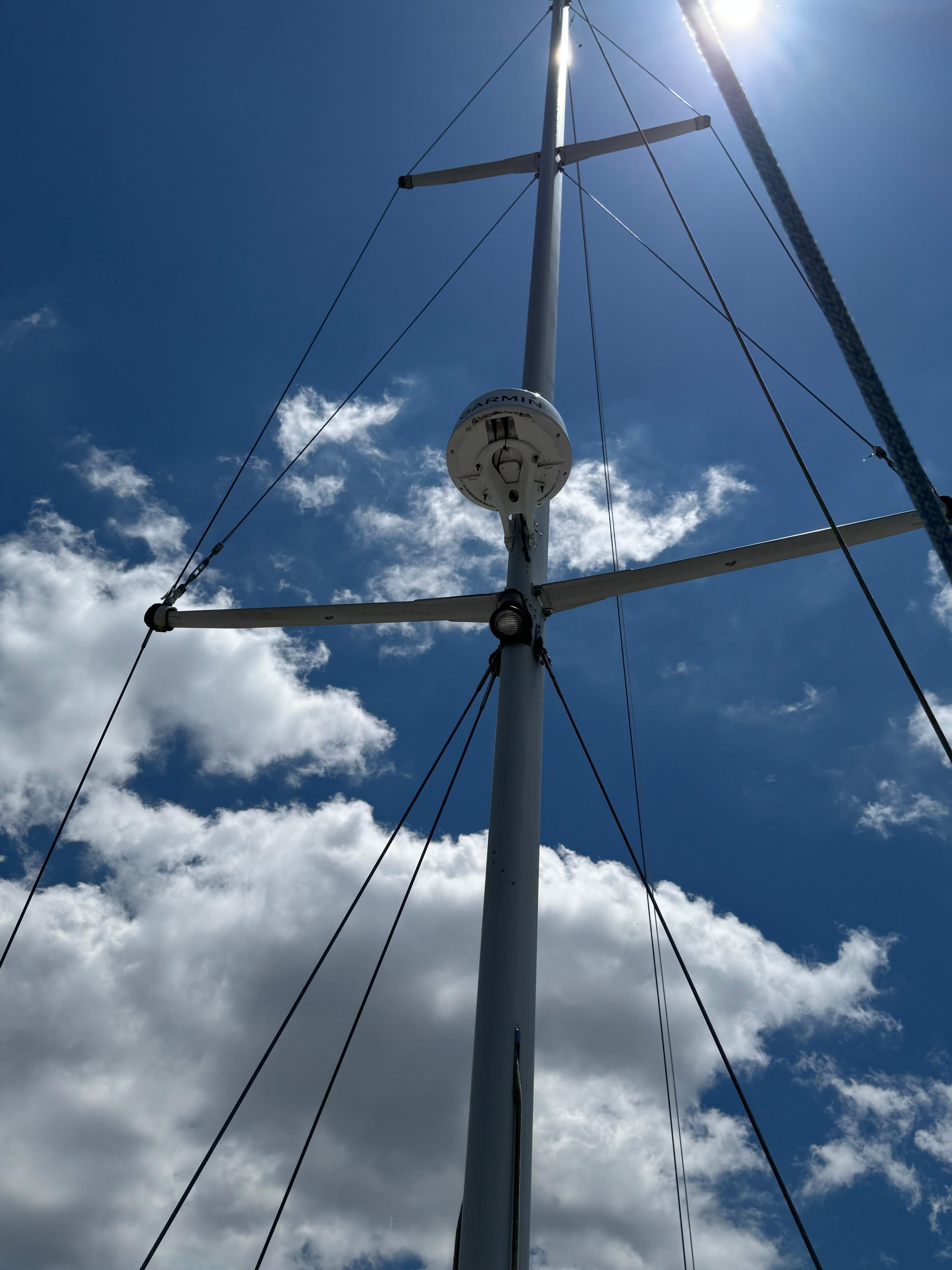 Mast of 1981 Gulfstar 44 sailboat against a bright blue sky with clouds.