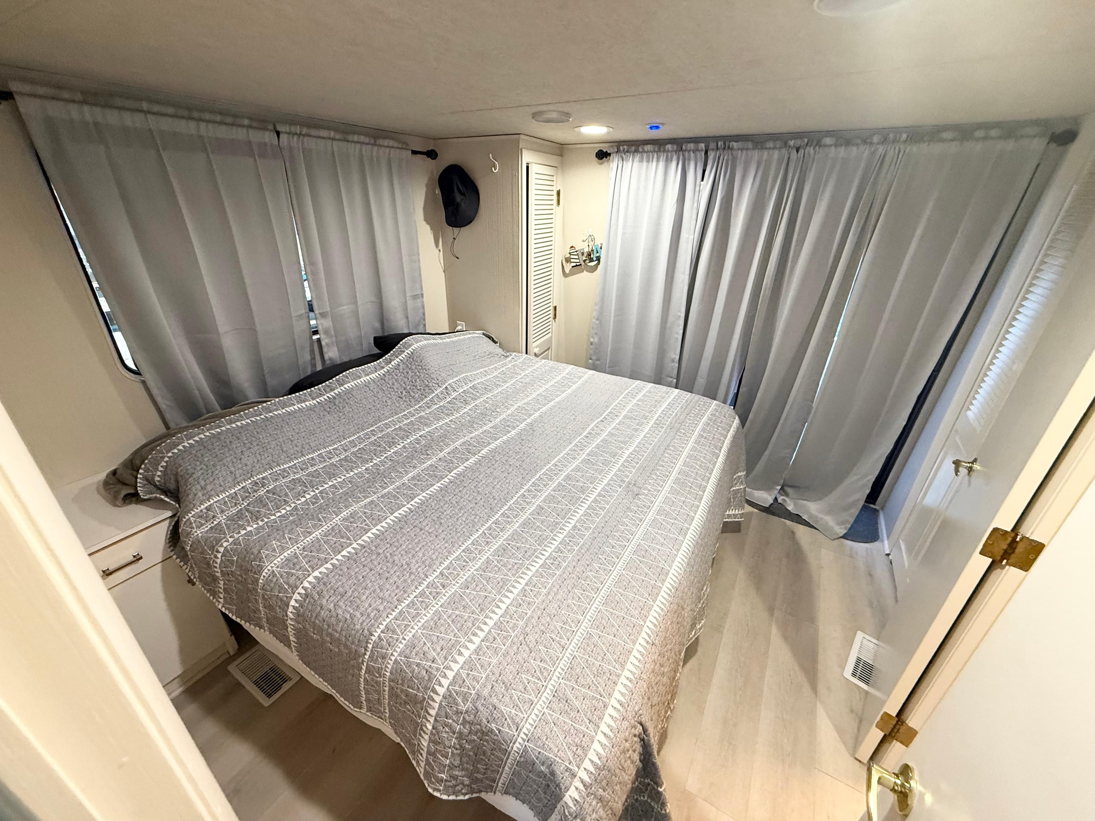 Cozy bedroom in 1995 Skipperliner 52 Inter-Coastal Motor Yacht with gray bedding and curtains.