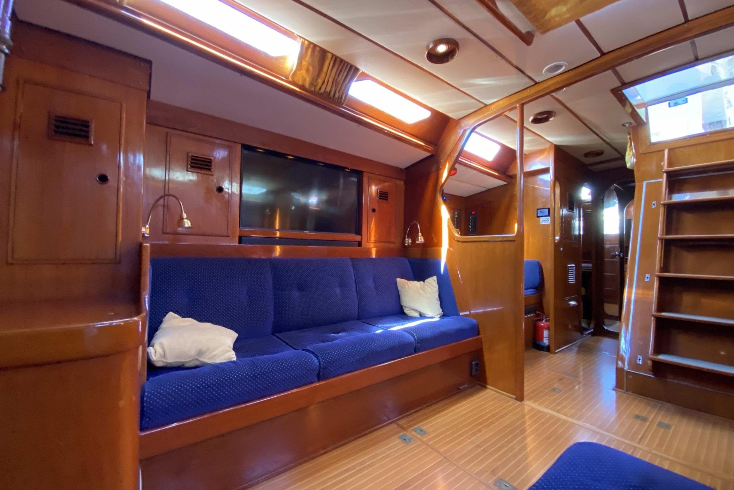 Luxurious 1983 Swan 70 yacht interior with blue seating and wooden finishes.