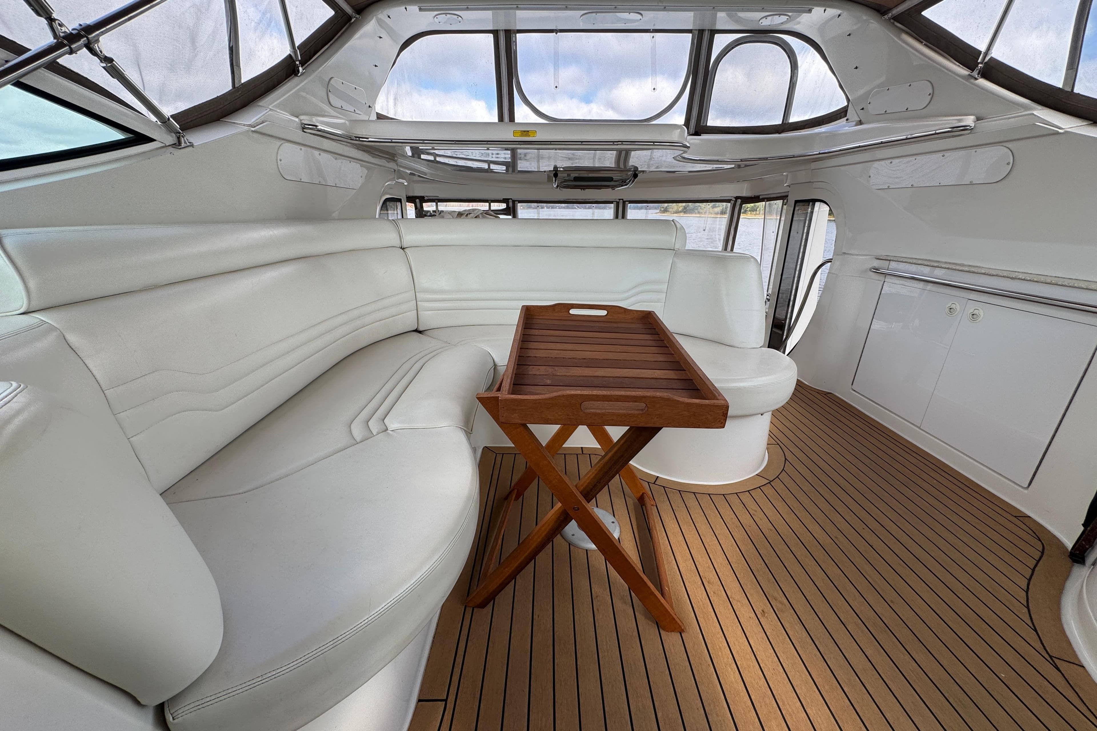 Luxurious interior of 2002 Carver 466 Motor Yacht with white seating and wooden table.