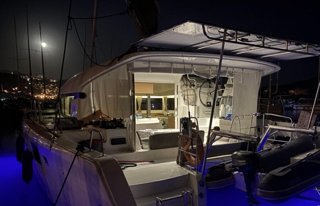 2016 Lagoon 39 catamaran illuminated at night, docked with city lights in the background.