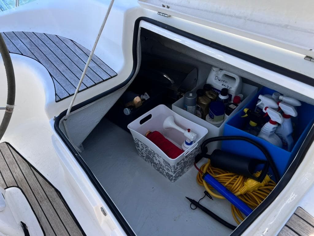 Storage compartment on a 2004 Bavaria 36 yacht with cleaning supplies and equipment.