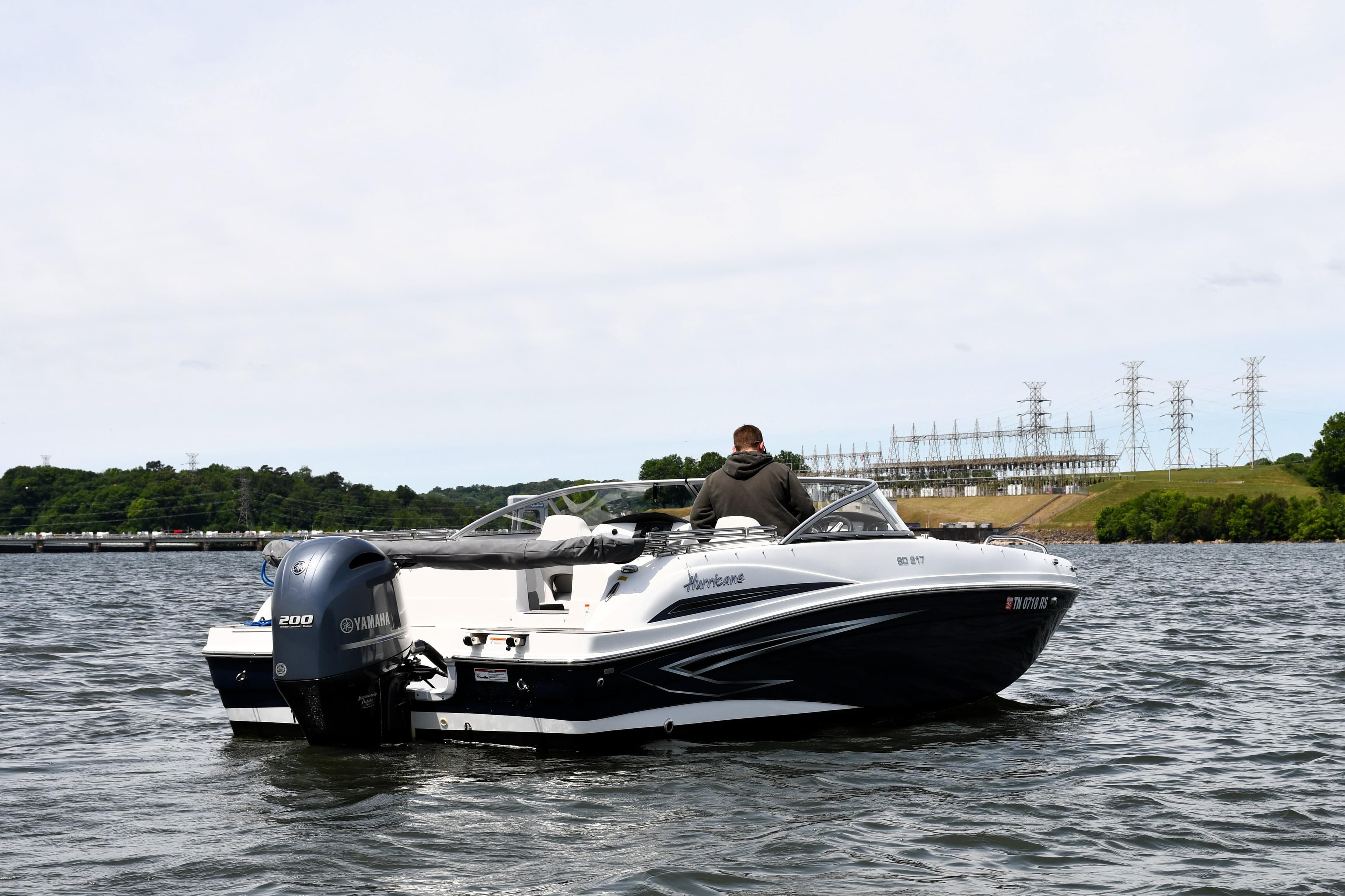 2023 Hurricane SunDeck 217 OB boat on water with Yamaha engine, scenic background.