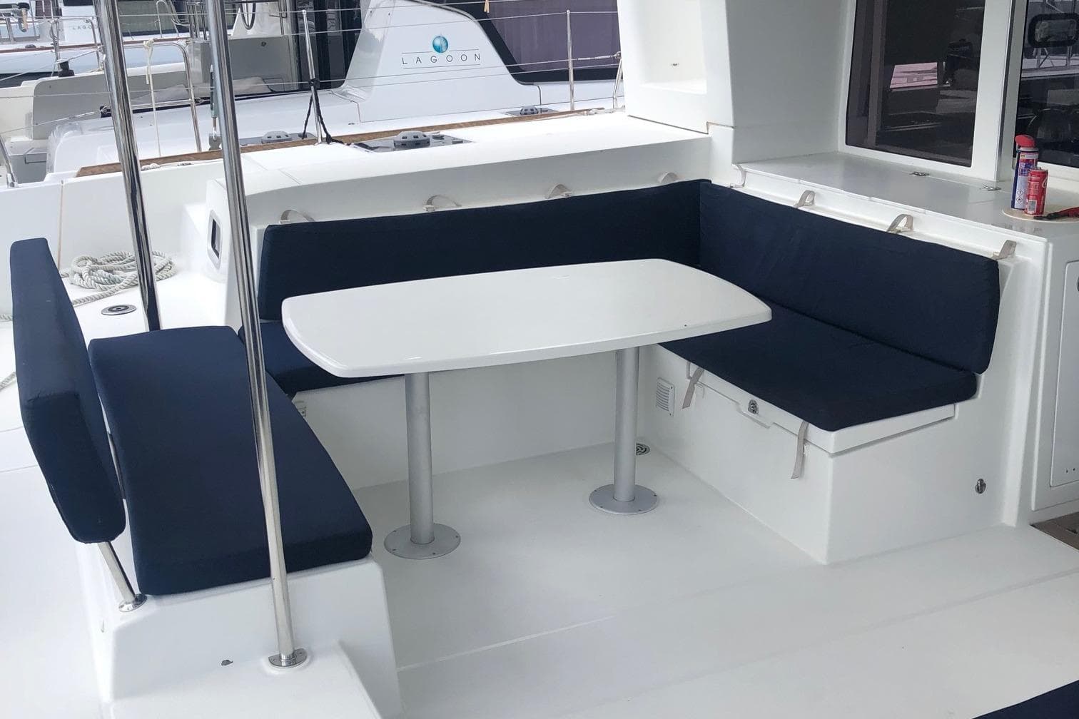 Outdoor seating area on 2018 Lagoon 450 catamaran with navy cushions and white table.