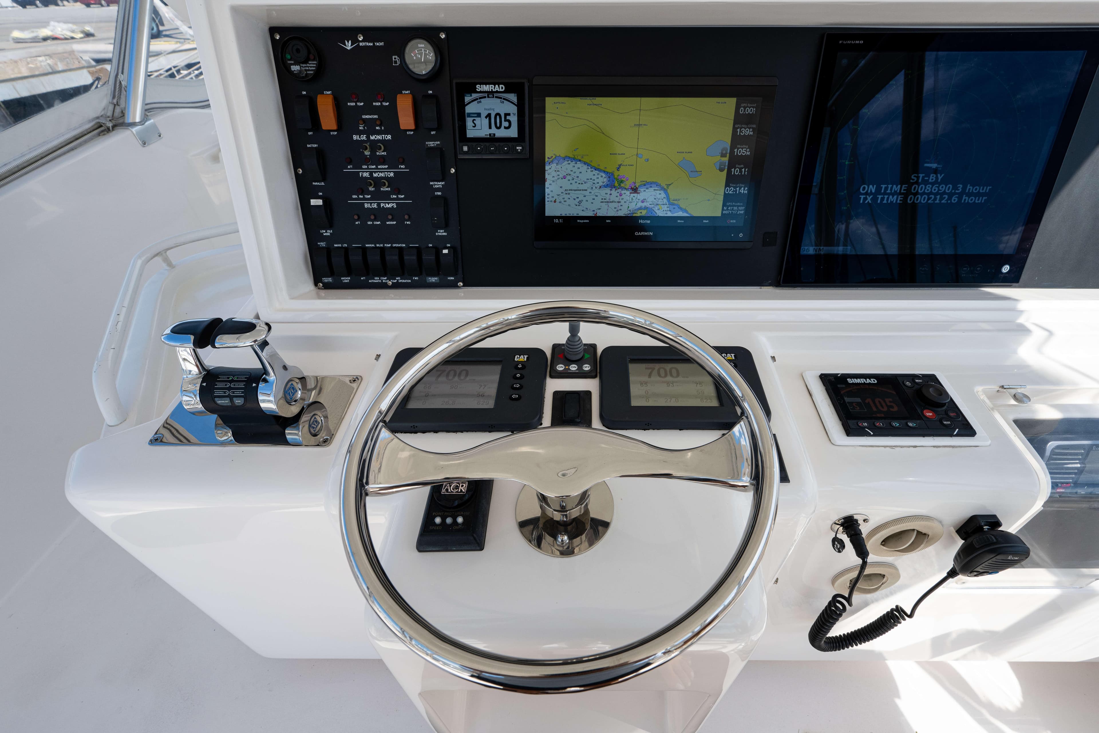 Control panel of a 2008 Bertram 570 yacht with navigation screens and steering wheel.