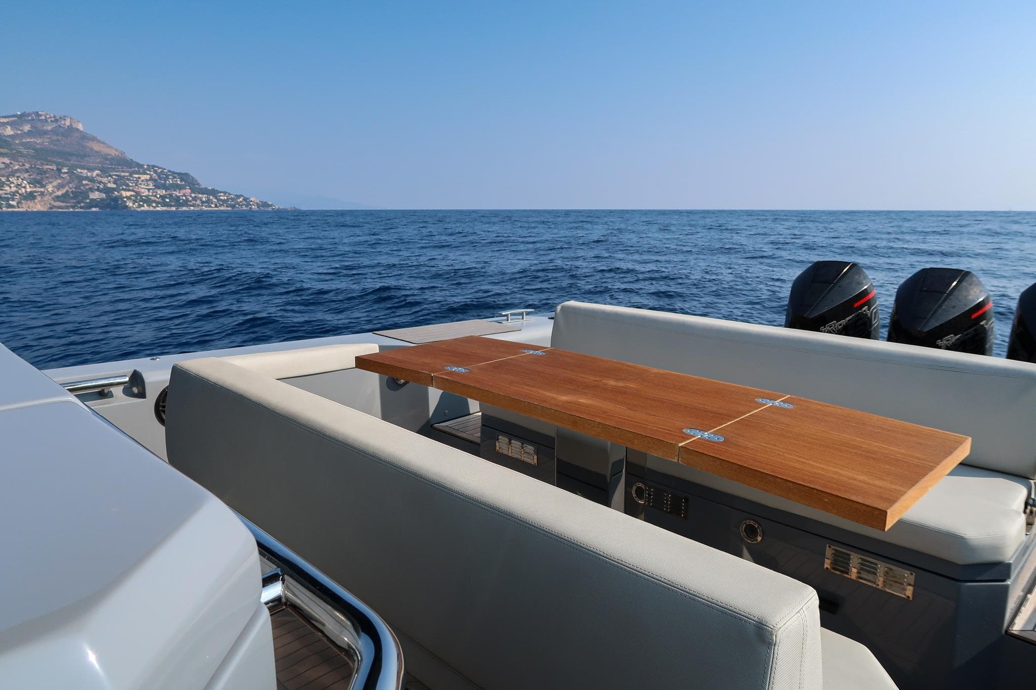 Luxury Pirelli 42 yacht deck with wooden table, scenic ocean view, 2023 model.