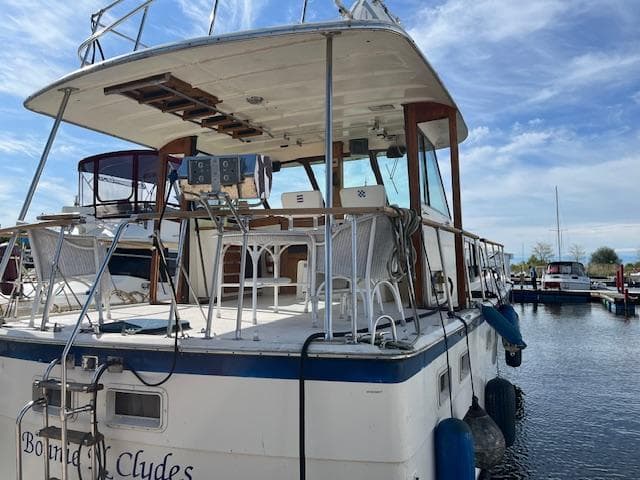 1977 Hatteras 43 Double Cabin yacht docked at marina under blue sky.