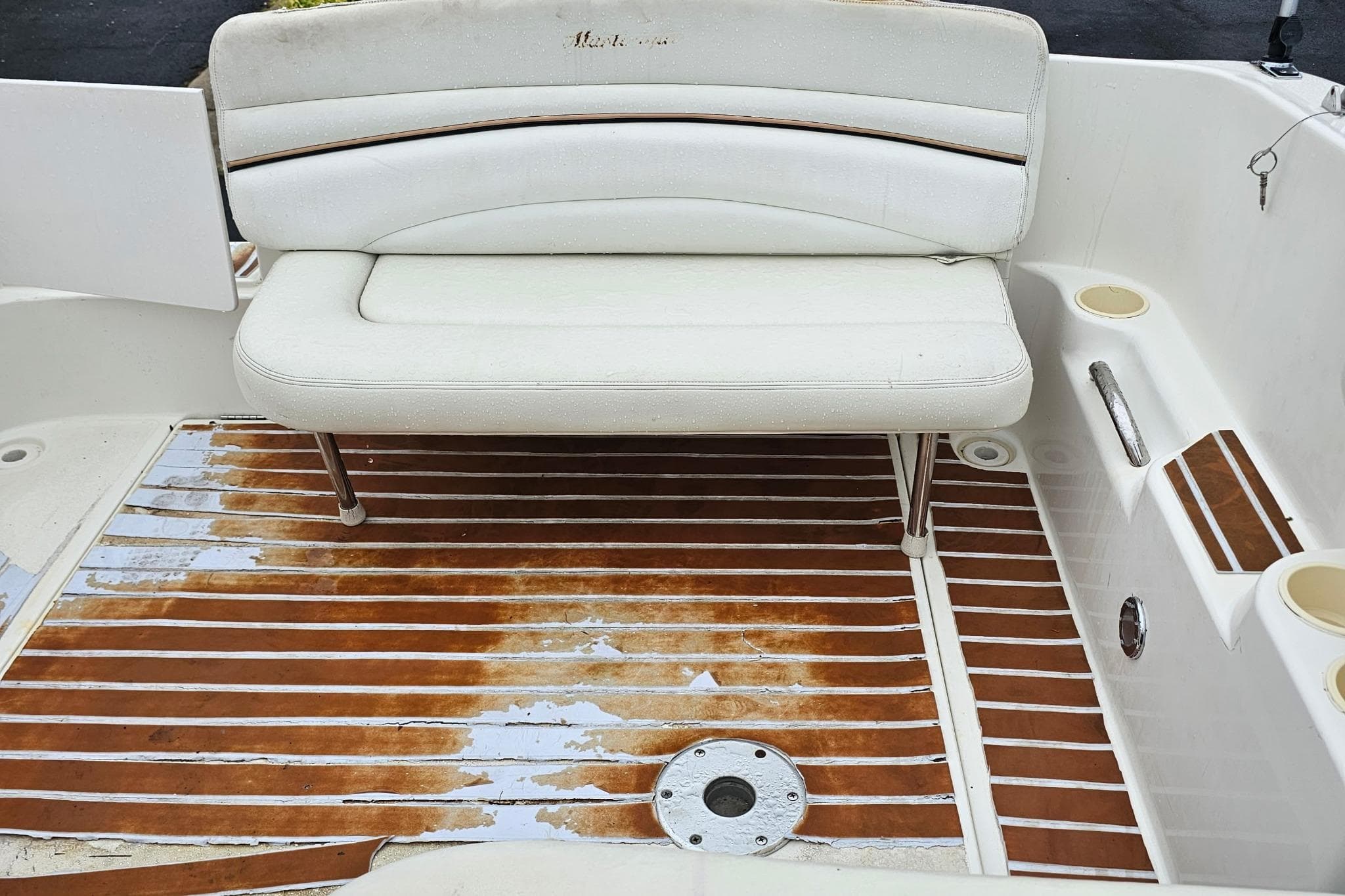 2002 Wellcraft 2600 Martinique boat interior with white seating and wooden deck flooring.