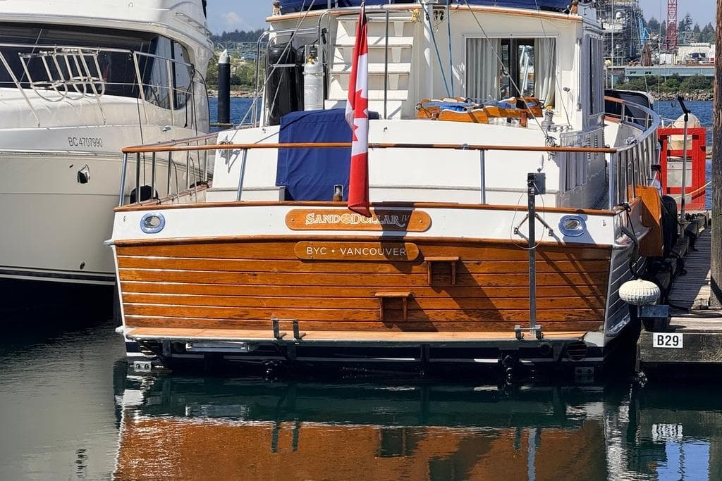 1983 Grand Banks 42 Classic yacht docked, featuring wooden exterior and Canadian flag.