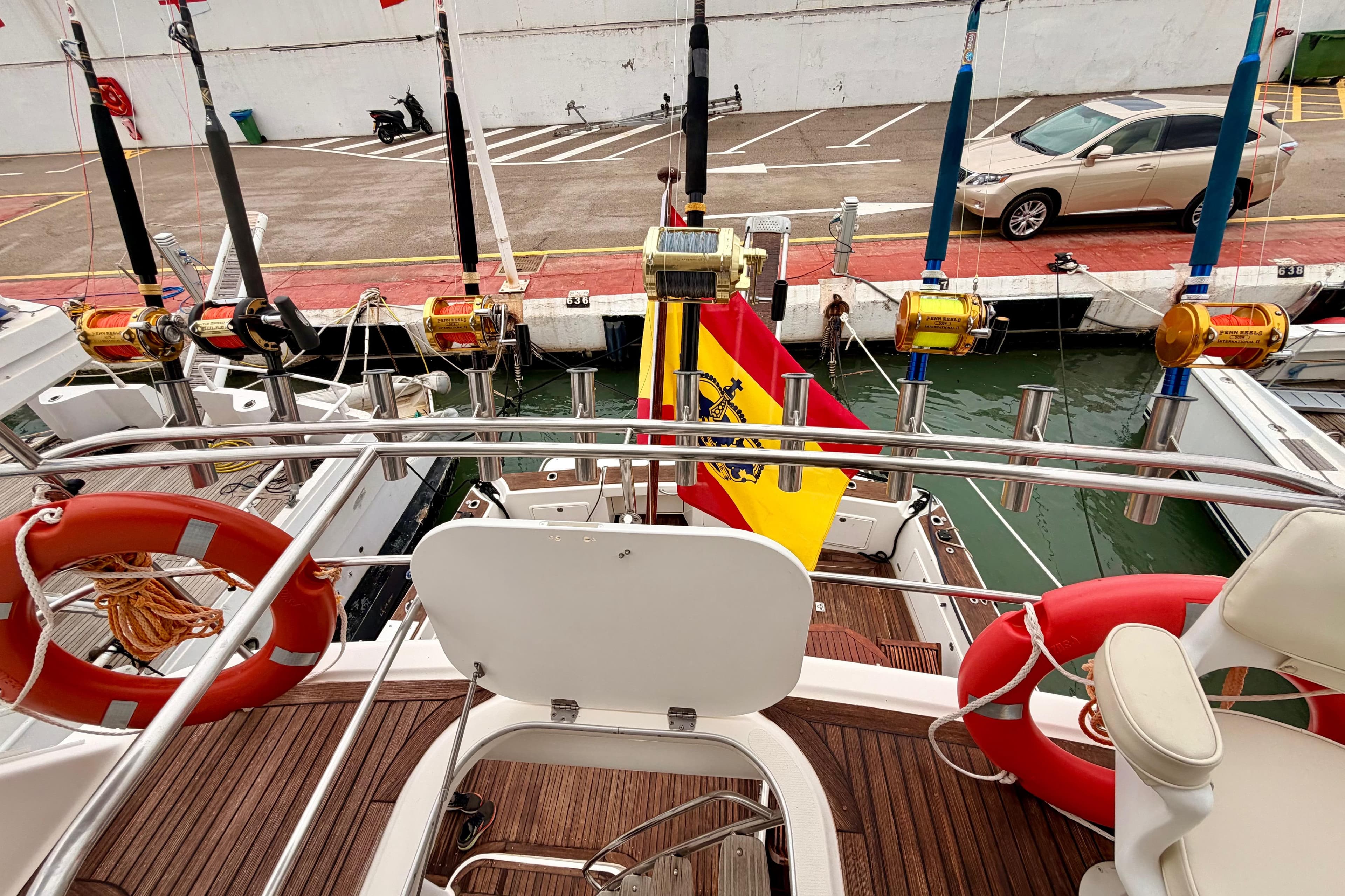 2004 Riviera 60 Flybridge yacht with fishing rods and Spanish flag at dock.