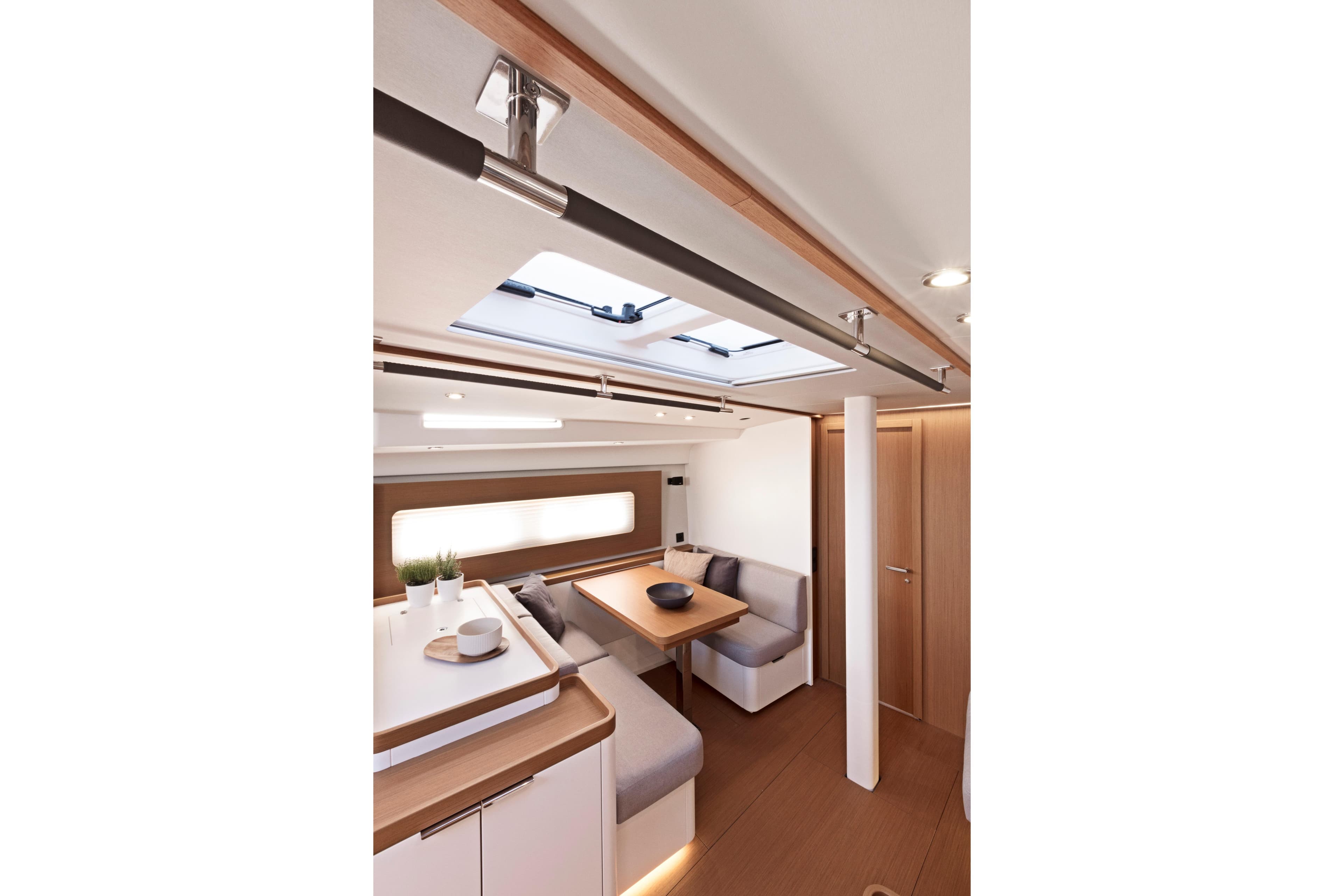 Luxurious interior of 2026 Beneteau First 53 yacht with modern dining area and skylight.
