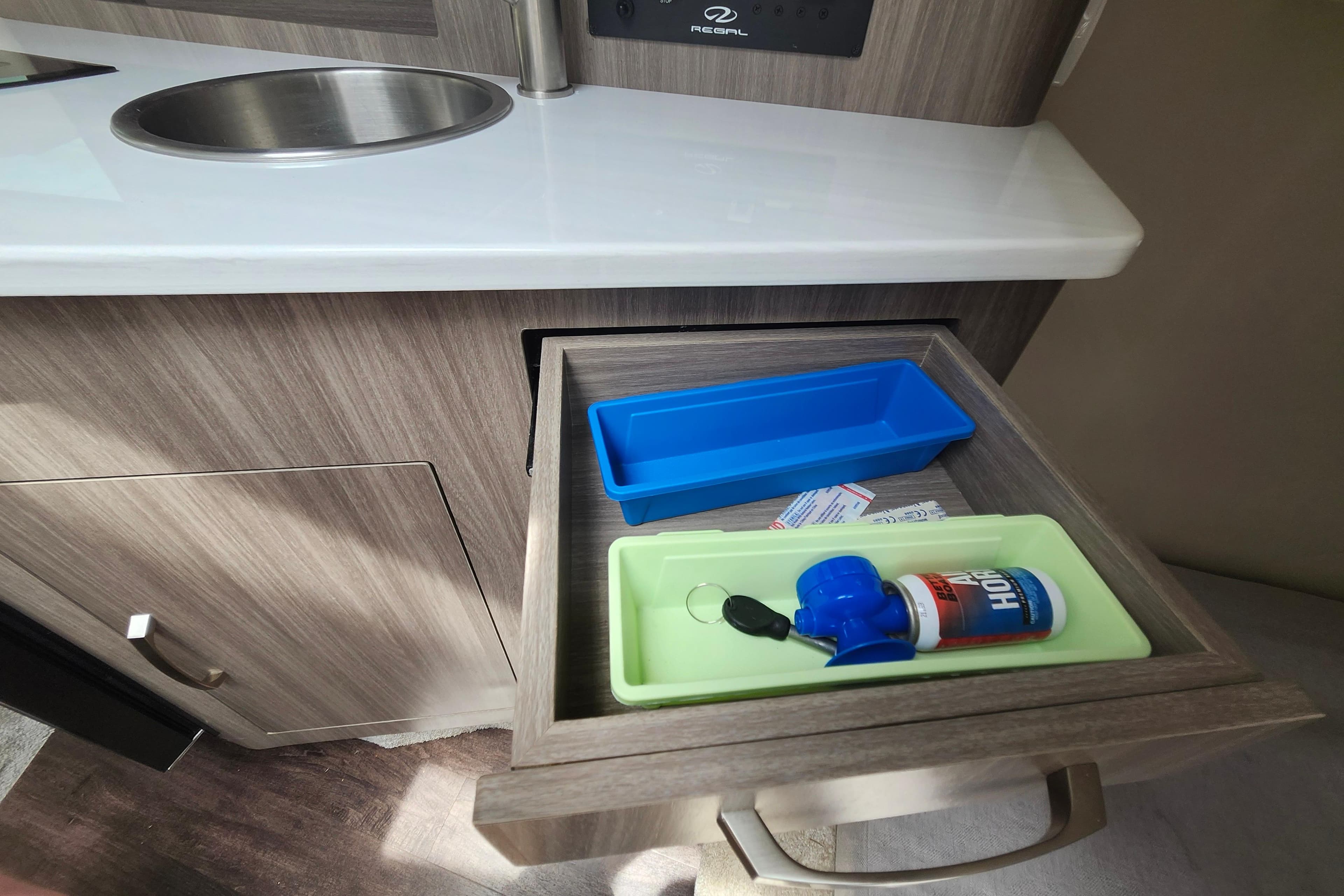 Open drawer in 2022 Regal 26 XO boat, featuring organized storage with trays and a horn.