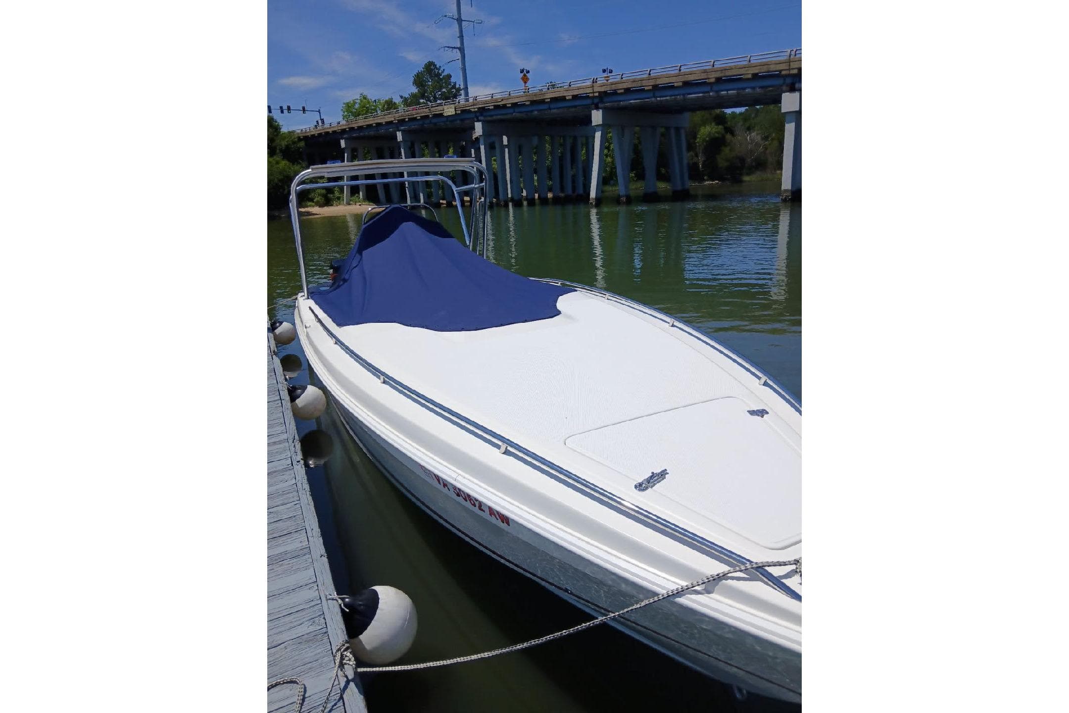1999 Wellcraft 302 Scarab Sport boat docked near a bridge, covered with a blue tarp.