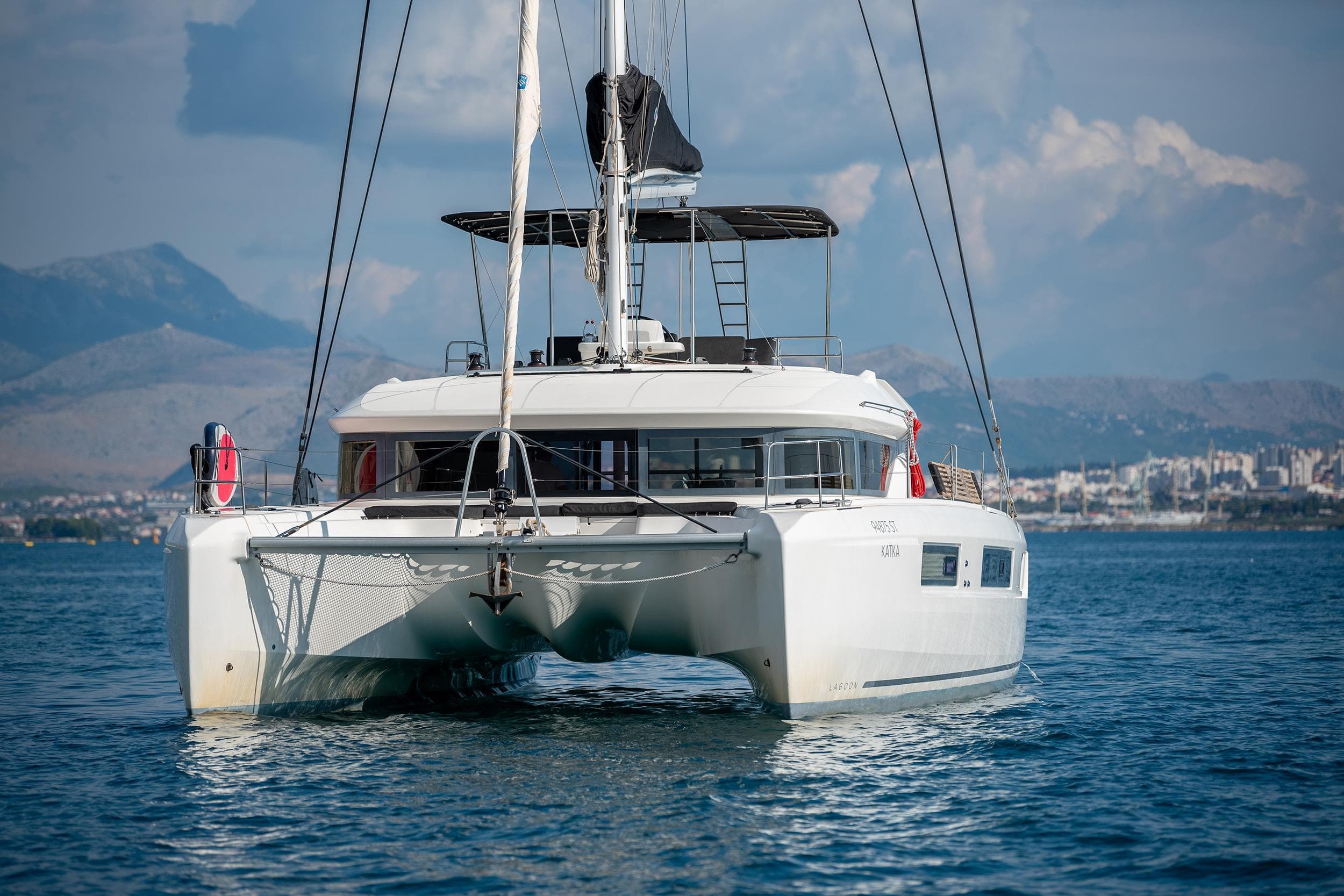 2019 Lagoon 50 catamaran sailing on calm waters with mountainous backdrop.