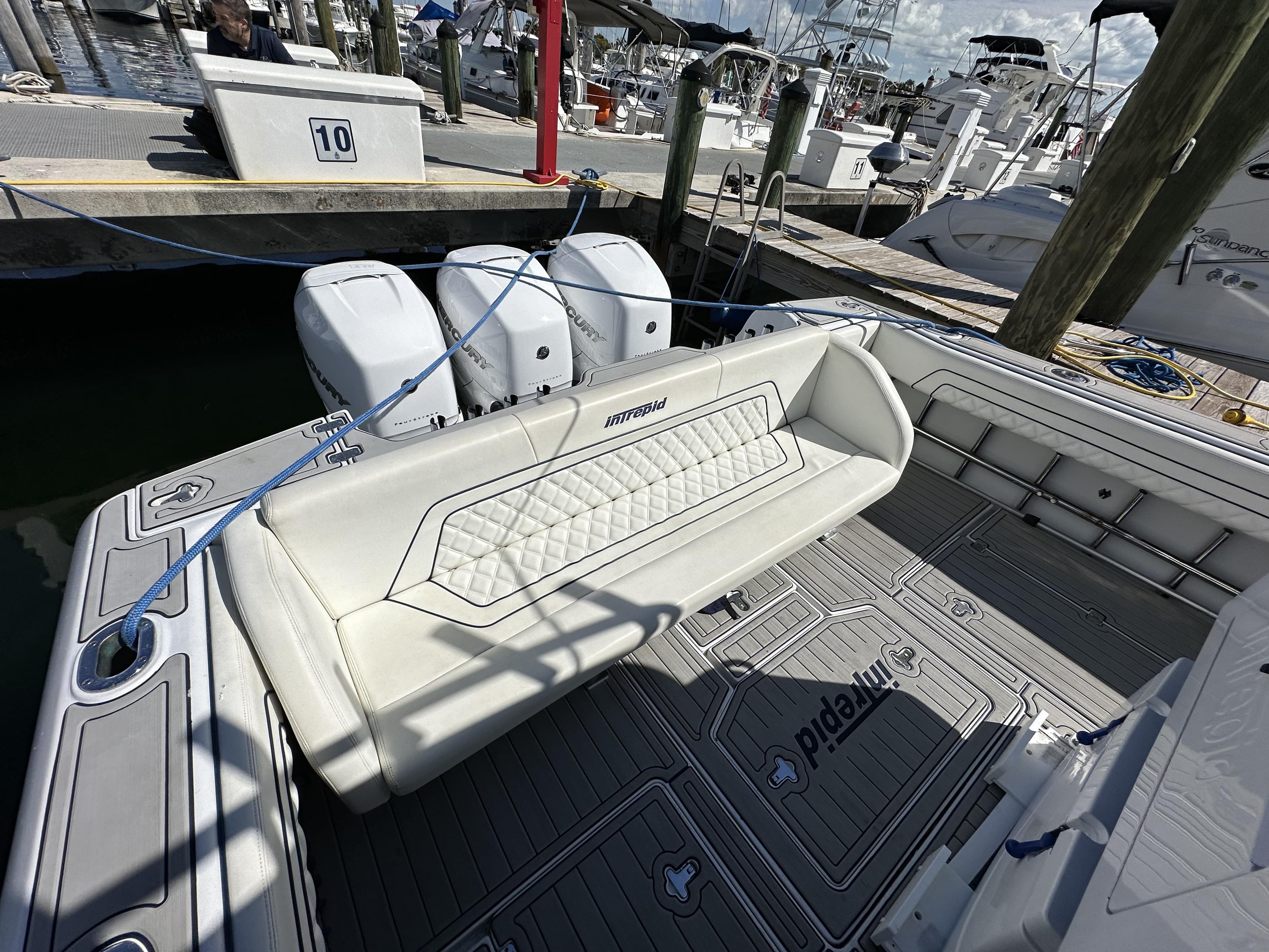 2002 Intrepid 377 Walkaround Cuddy boat with triple outboard engines docked at marina.