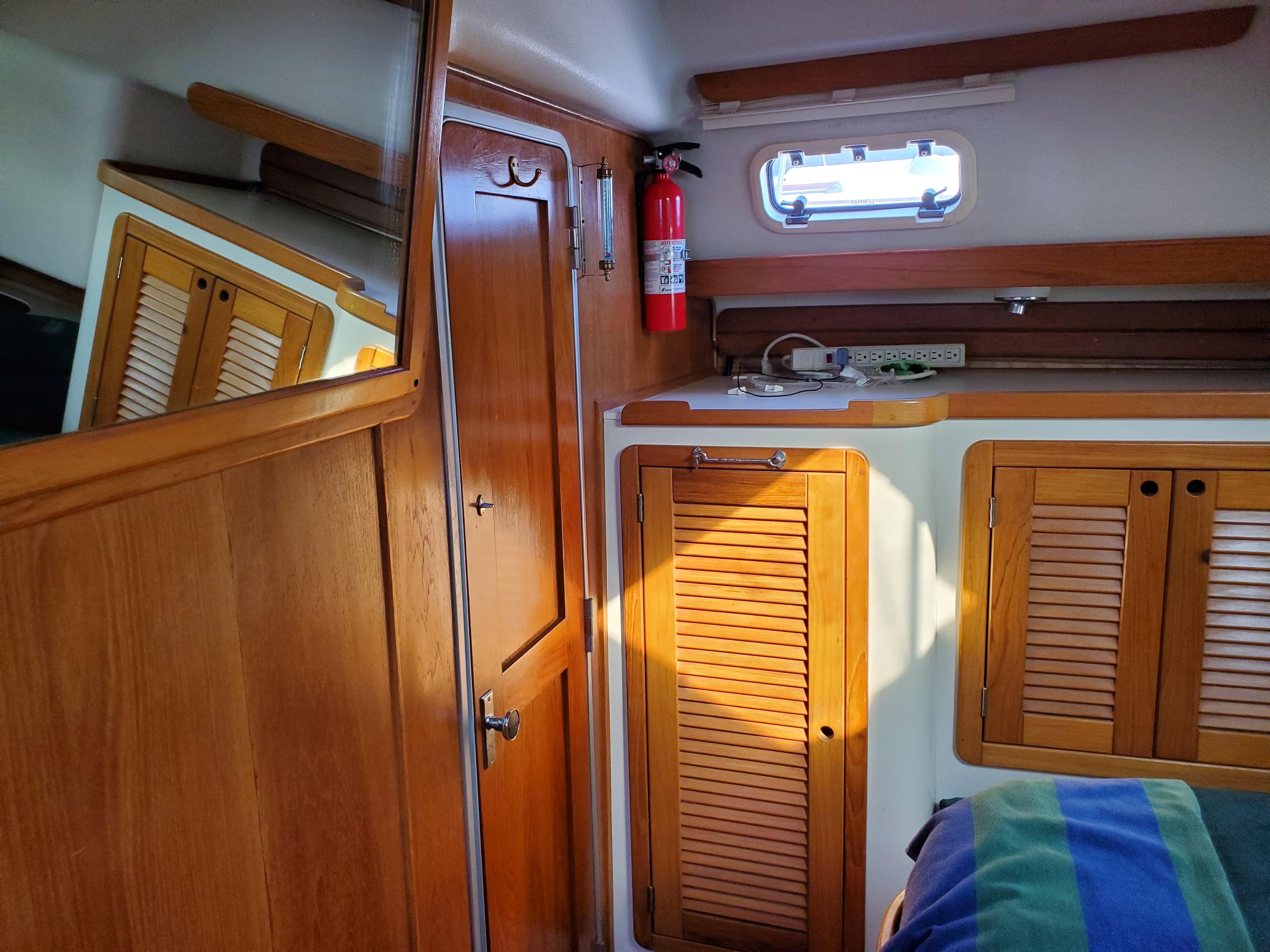 Interior of 1997 Catalina Morgan 38 sailboat with wooden cabinets and a small window.
