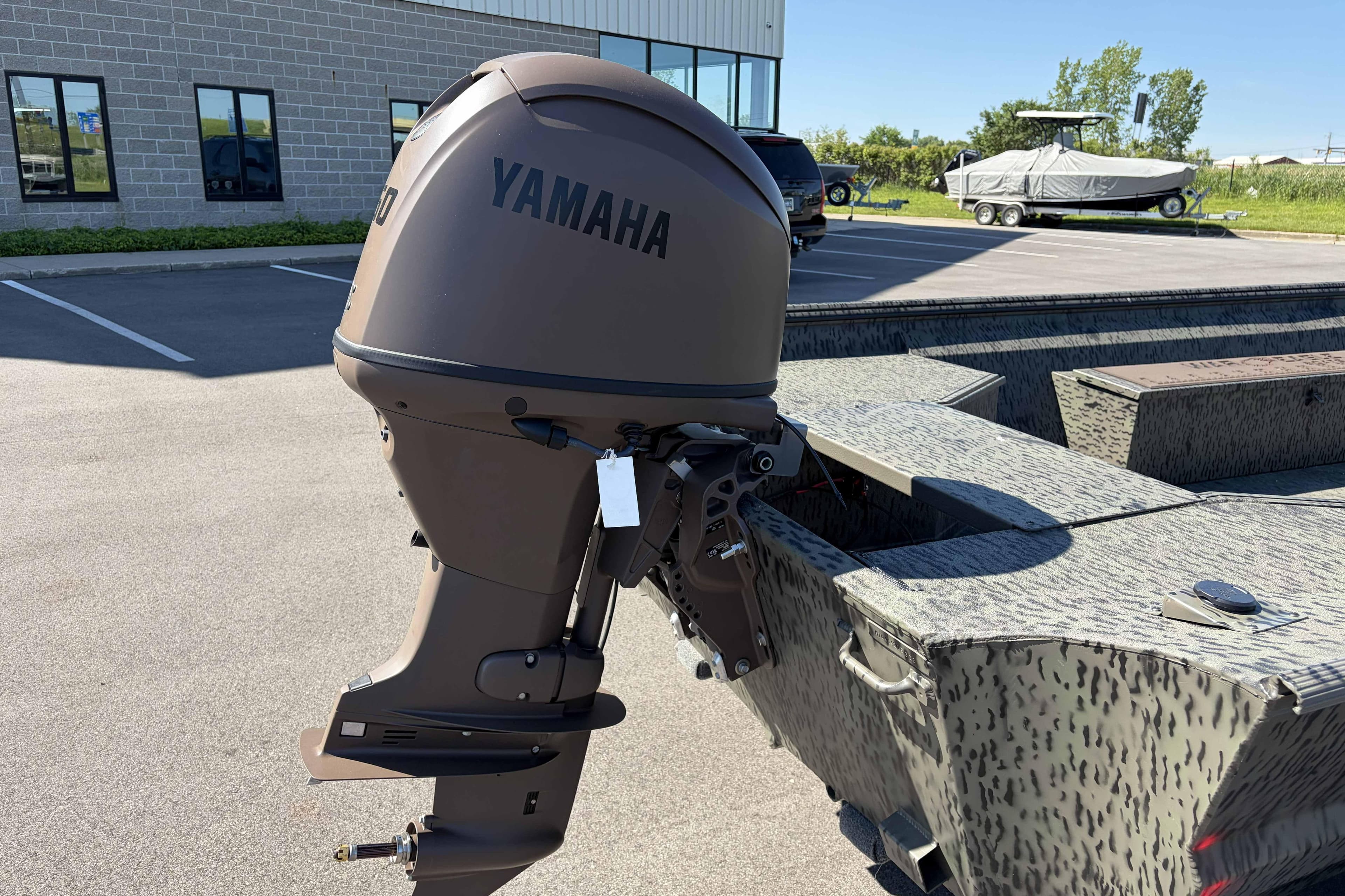 Outboard motor on a 2026 War Eagle 860LDV boat in a parking lot.