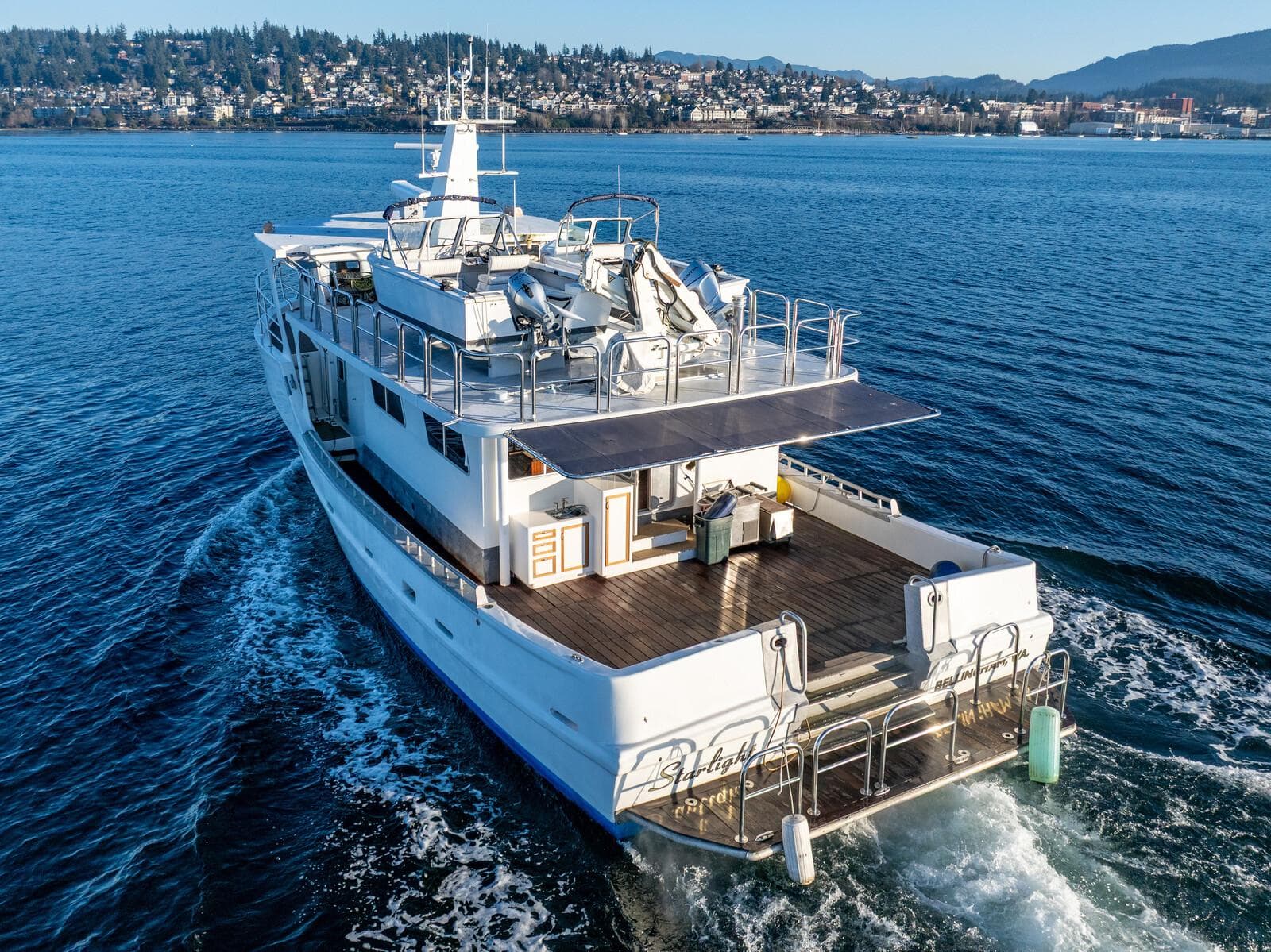 Custom Expedition Vessel 58, 1986, cruising on a scenic waterway with cityscape in the background.