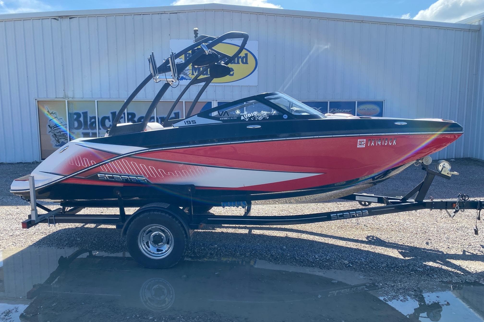 2014 Scarab 195 H.O. Impulse boat on trailer, red and white design, parked outdoors.