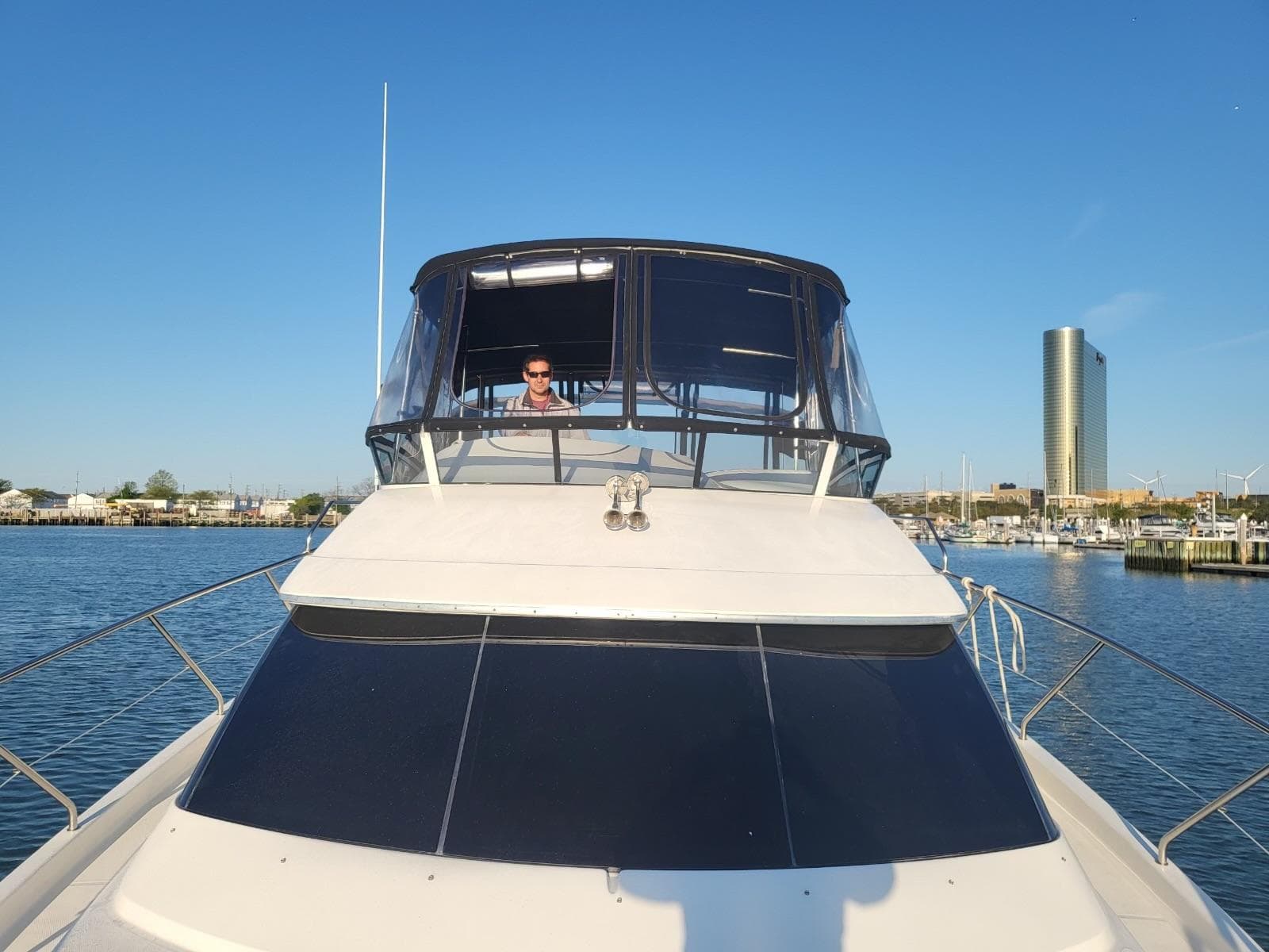 2003 Silverton 410 Sport Bridge yacht on calm water with city skyline in background.