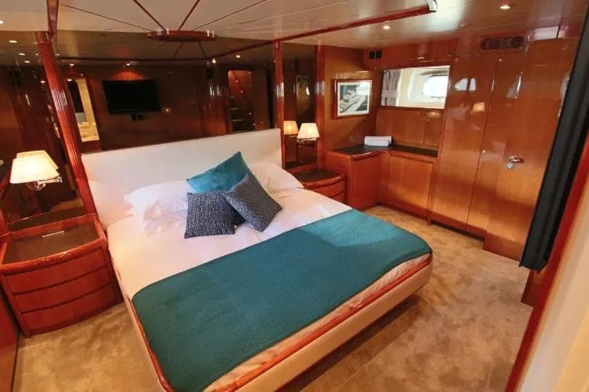 Luxurious bedroom interior on a 1999 Falcon 86 yacht with elegant wood finishes.