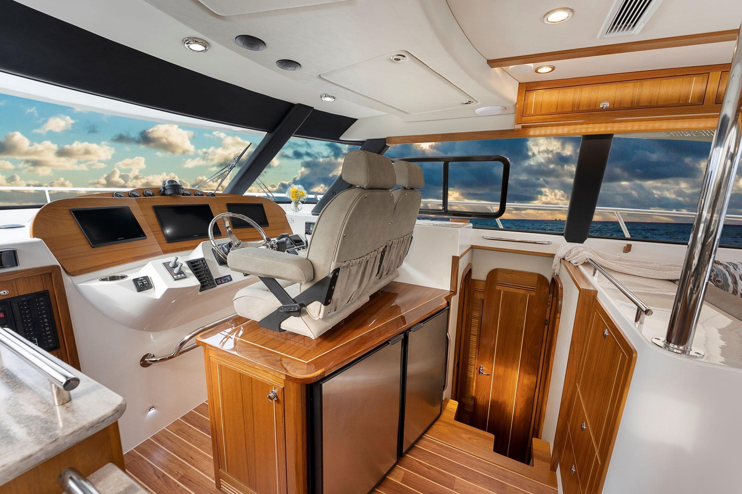 2026 Aspen C128 Flybridge interior with modern helm, wooden accents, and ocean view.