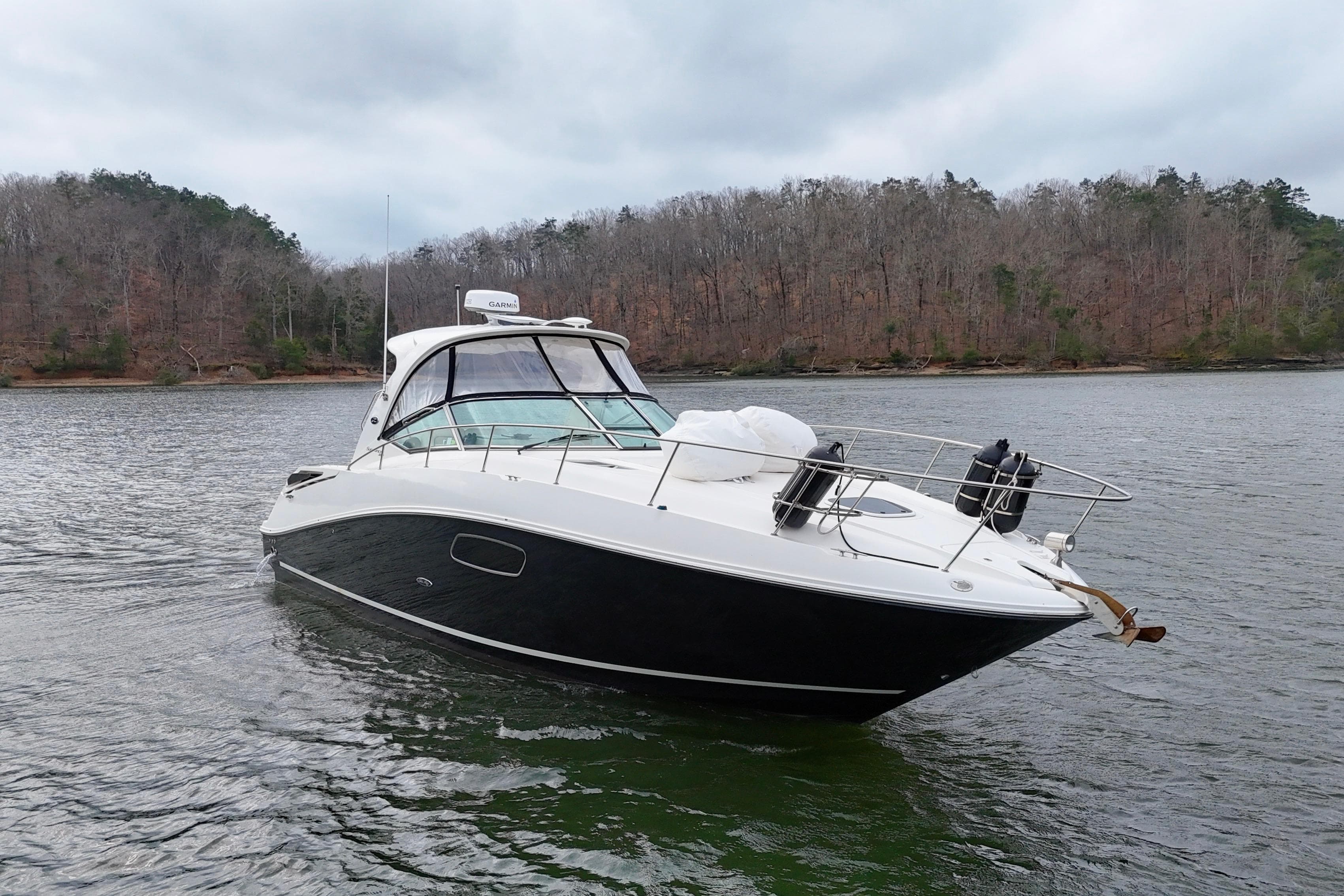 2009 Sea Ray Sundancer 350 yacht on a calm lake with forested shoreline.