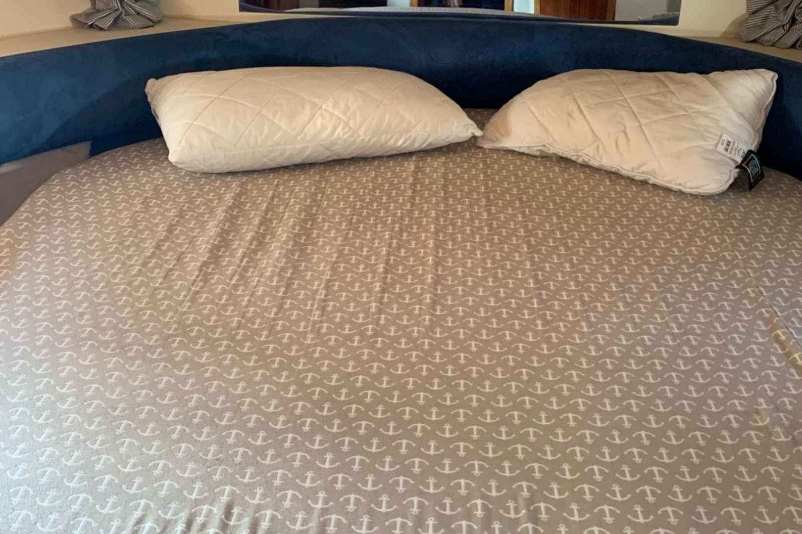Round bed with anchor-patterned sheets and pillows on a Princess V42 yacht, 2000 model.