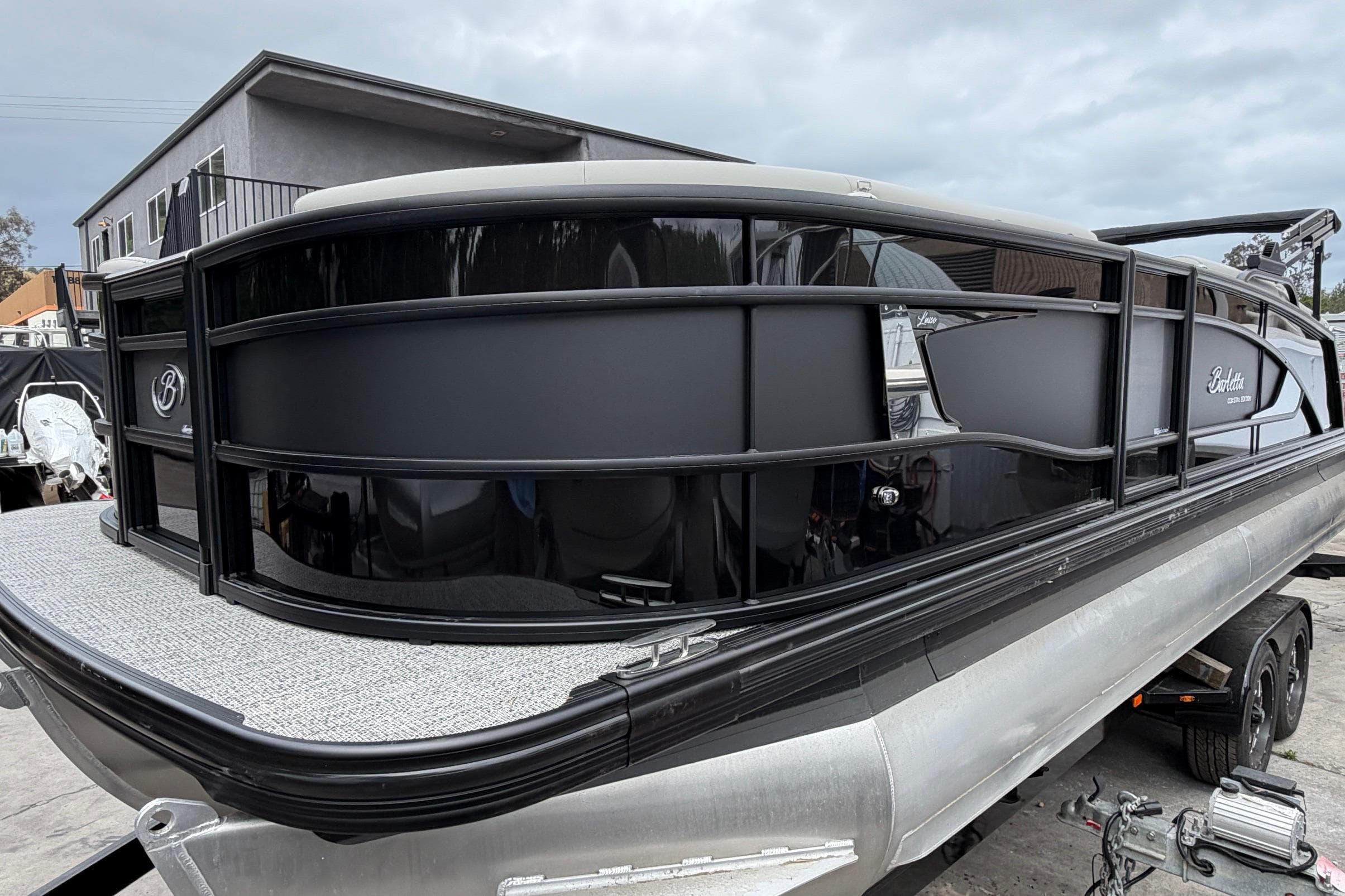 2026 Barletta Lusso 23M pontoon boat on trailer, sleek black design.