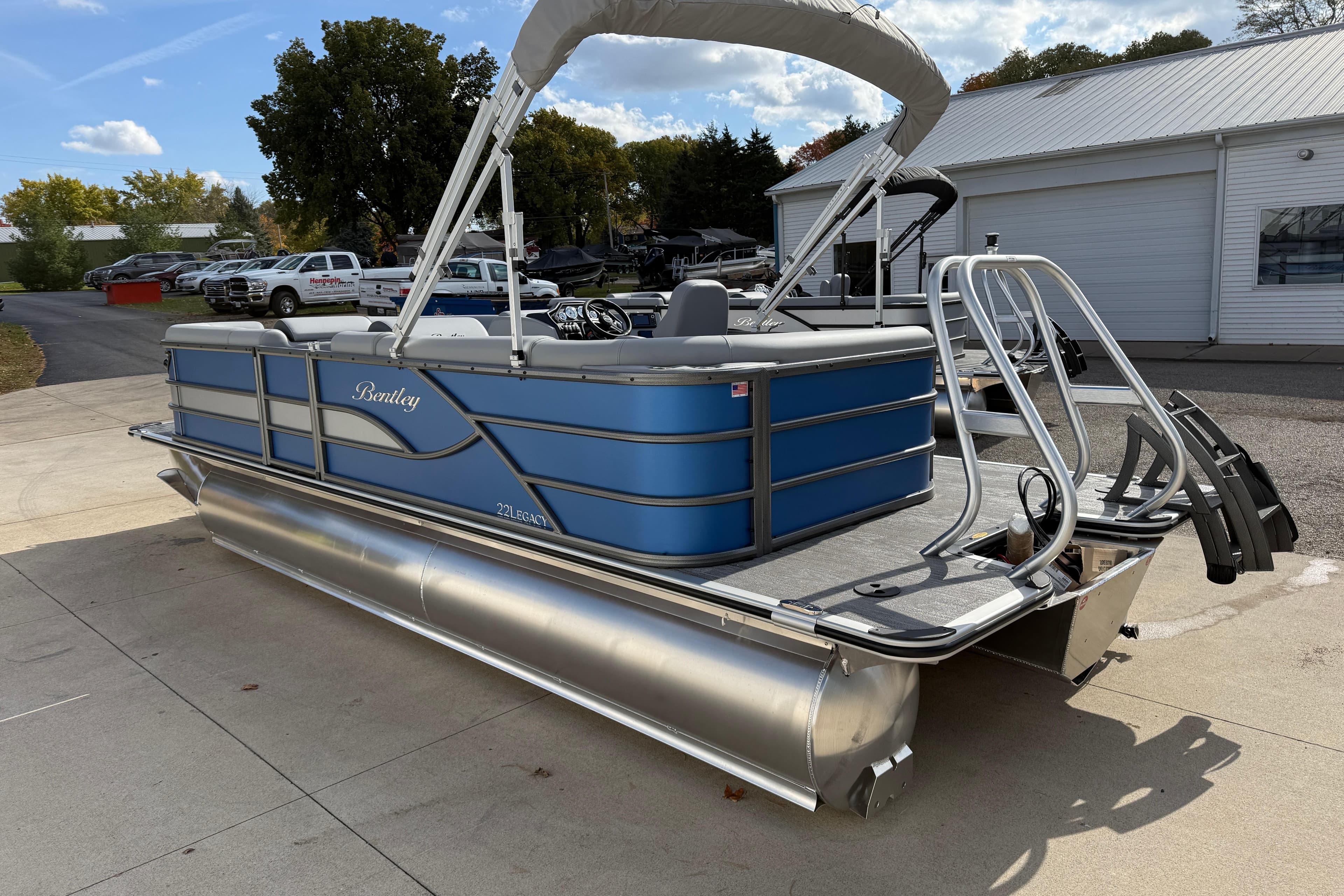 2026 Bentley Pontoons Legacy 223 Cruise XL, blue pontoon boat, parked outdoors.