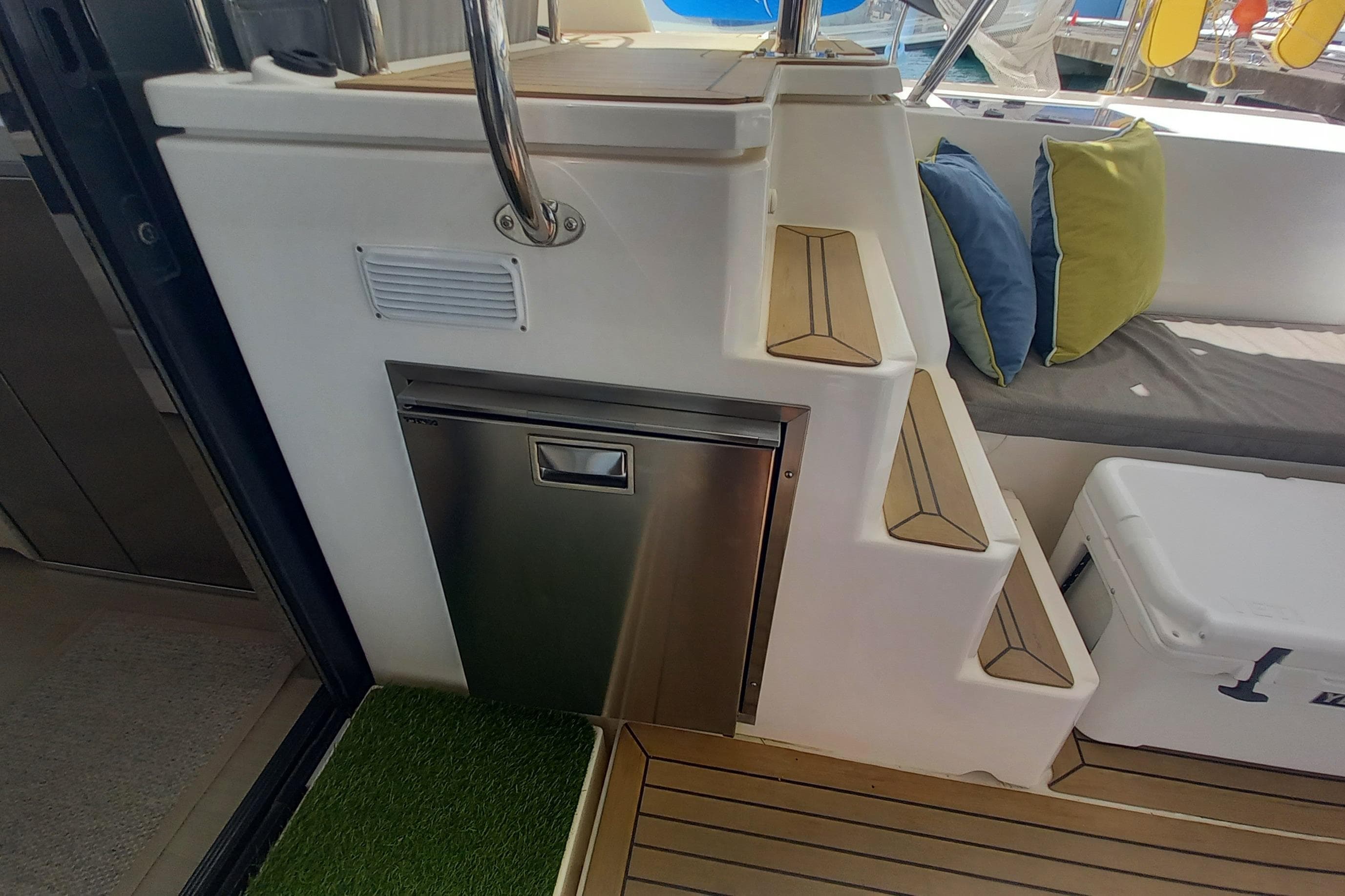 Staircase and seating area on a 2019 Leopard 45 yacht, featuring cushions and a stainless steel appliance.
