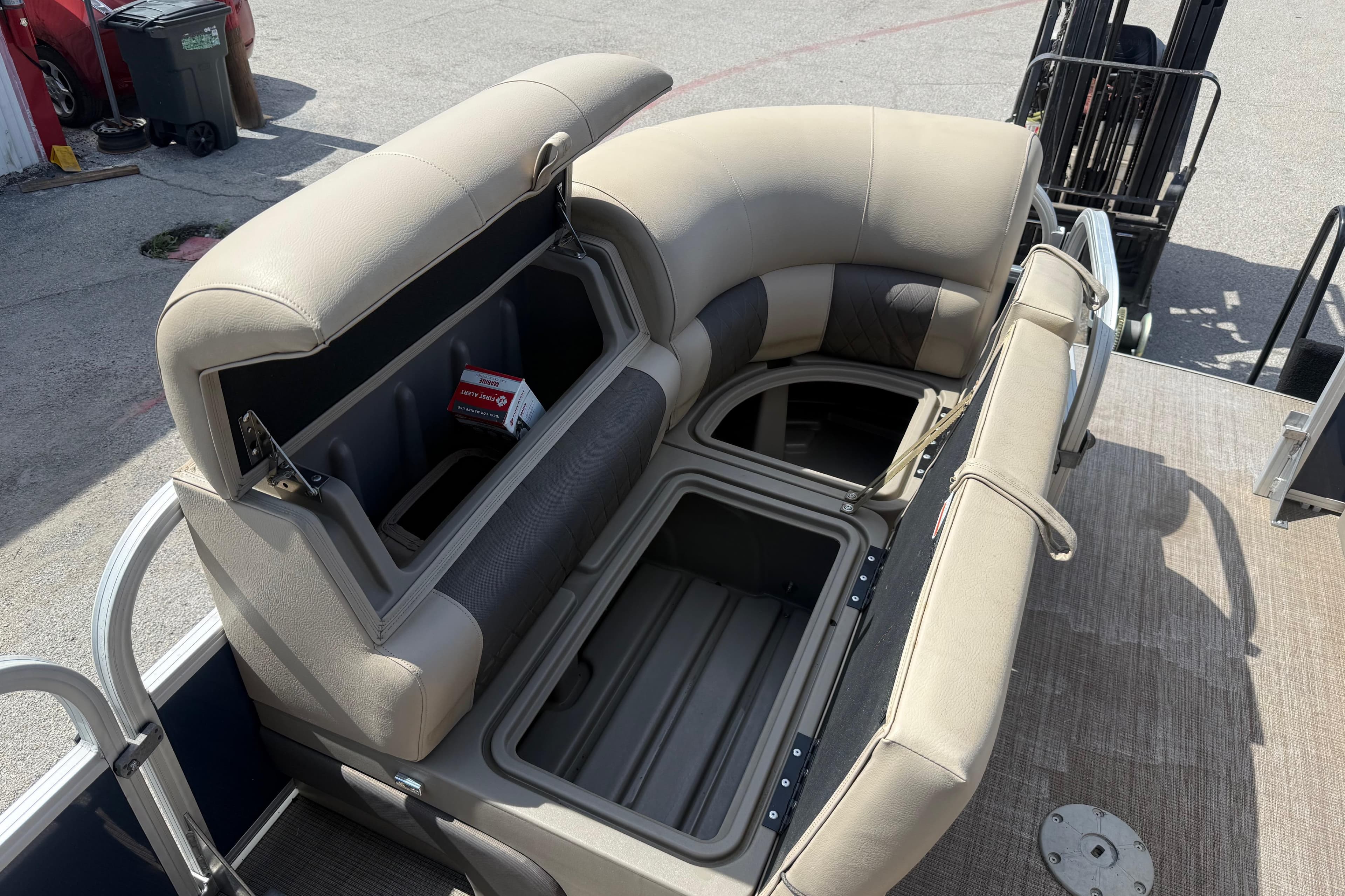 2021 Sun Tracker SportFish 22 DLX pontoon boat with open storage compartments and beige seating.