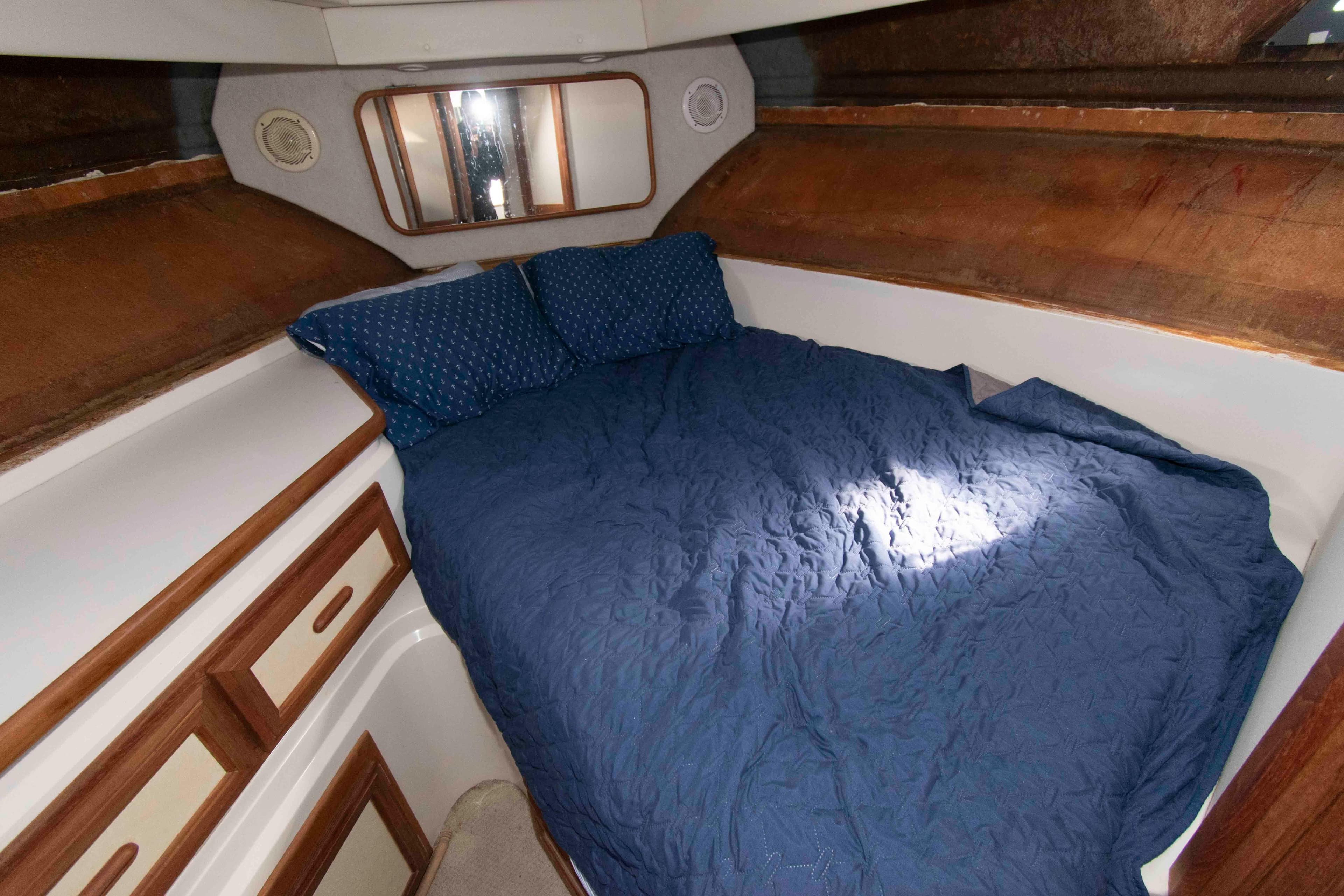 Cozy cabin interior of 1995 Carver 330 Mariner with blue bedding and wooden accents.