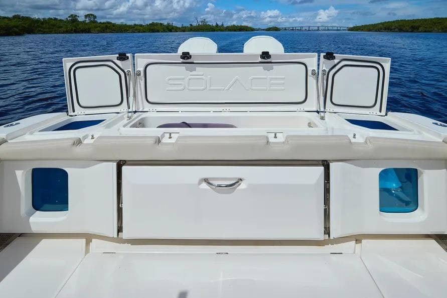 2022 Solace 41 CS boat deck with storage compartments open, on a serene water backdrop.