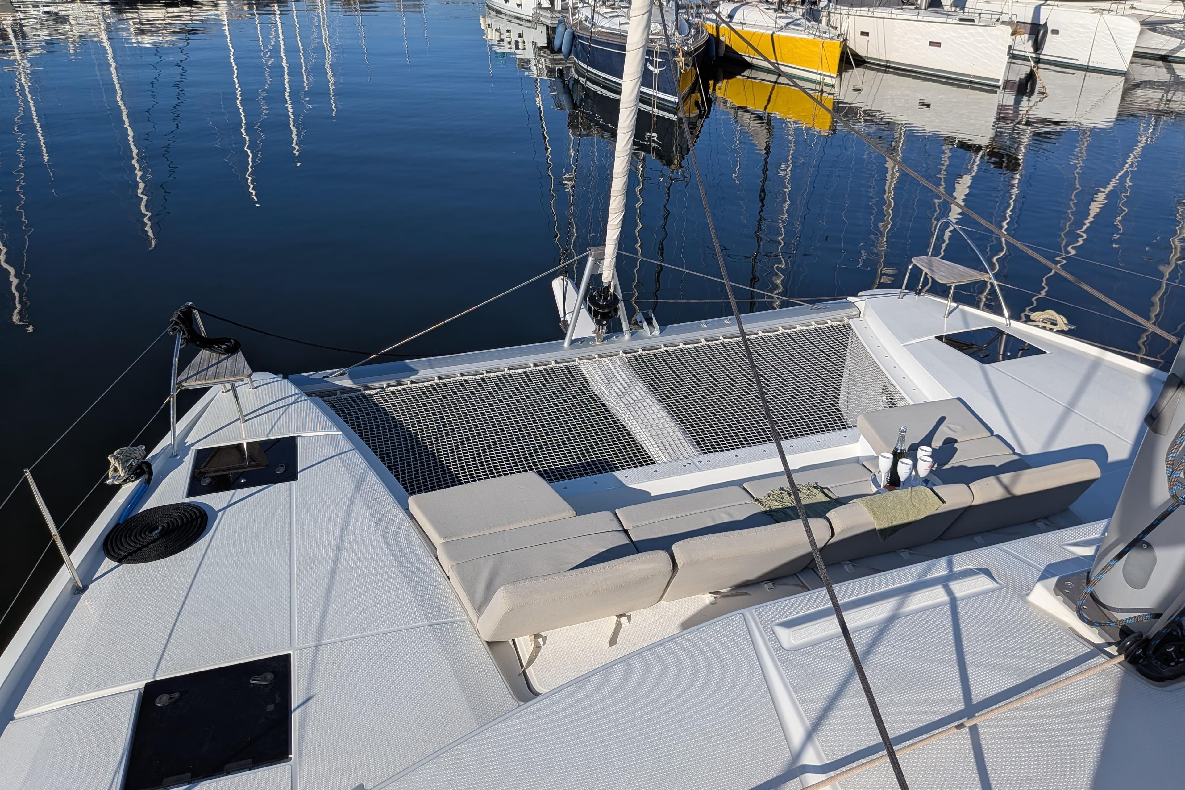 2024 Fountaine Pajot Astrea 42 Catamaran deck with seating and netting, docked in marina.