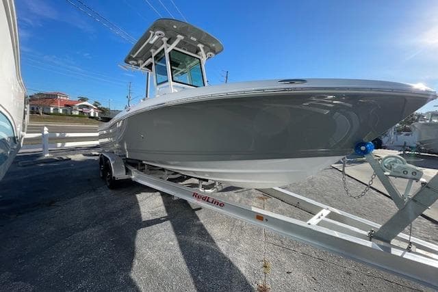 2026 Caymas 24 HB boat on trailer, sleek design, parked outdoors under clear blue sky.