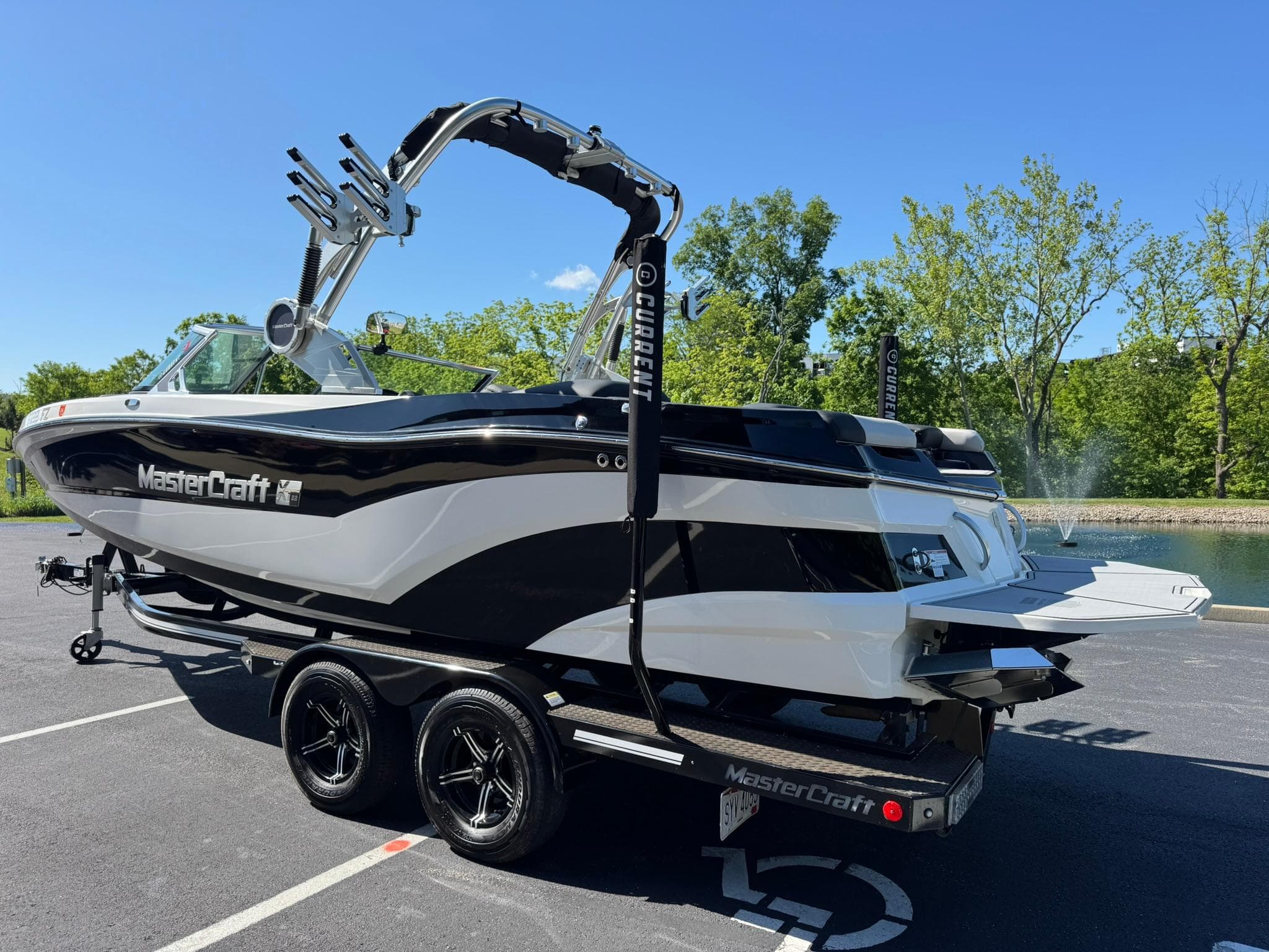 2020 MasterCraft XT22 boat on trailer, parked outdoors, with trees in the background.