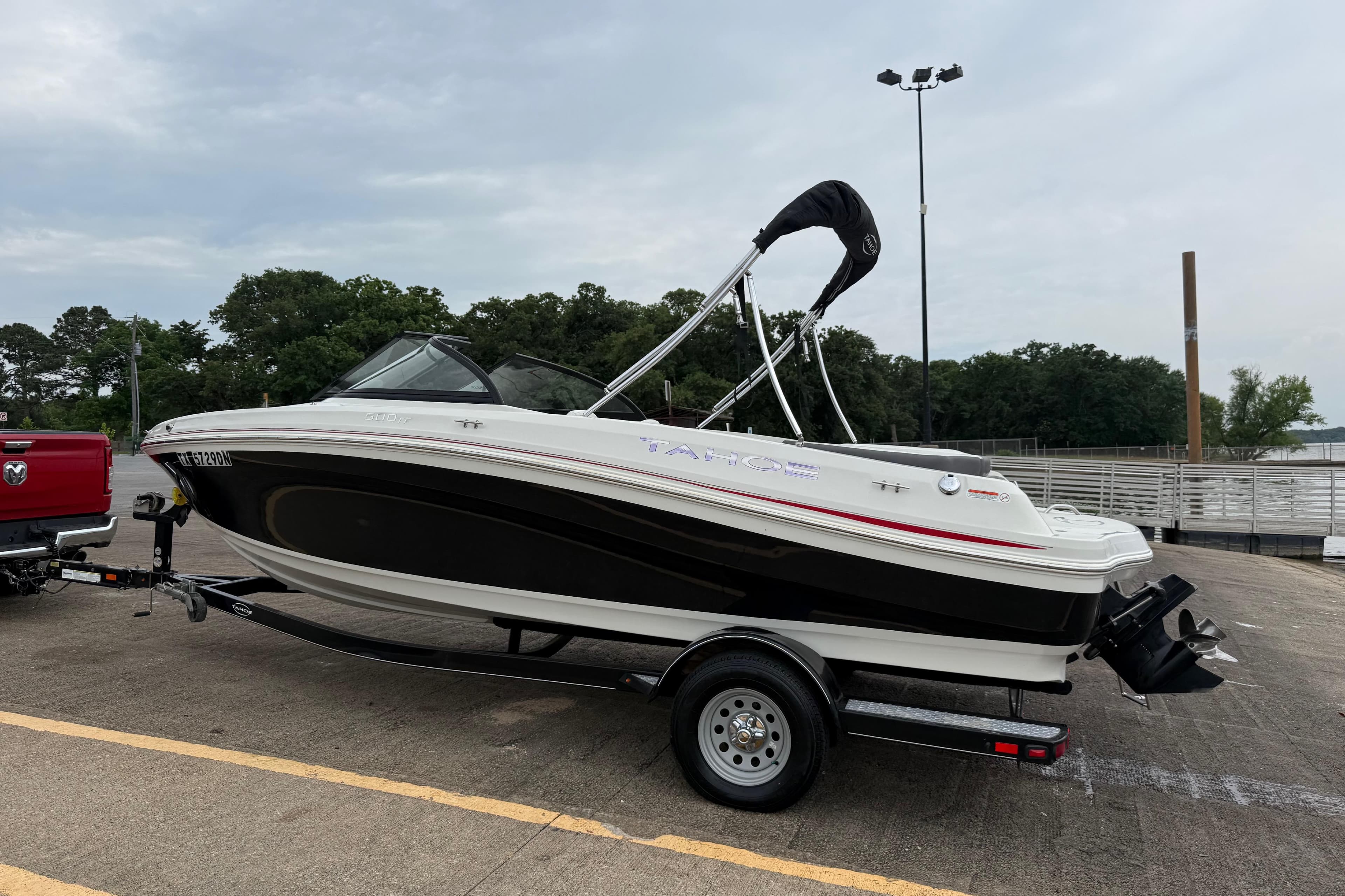 2016 Tahoe 500 TF boat on trailer, parked near a lake with trees in the background.