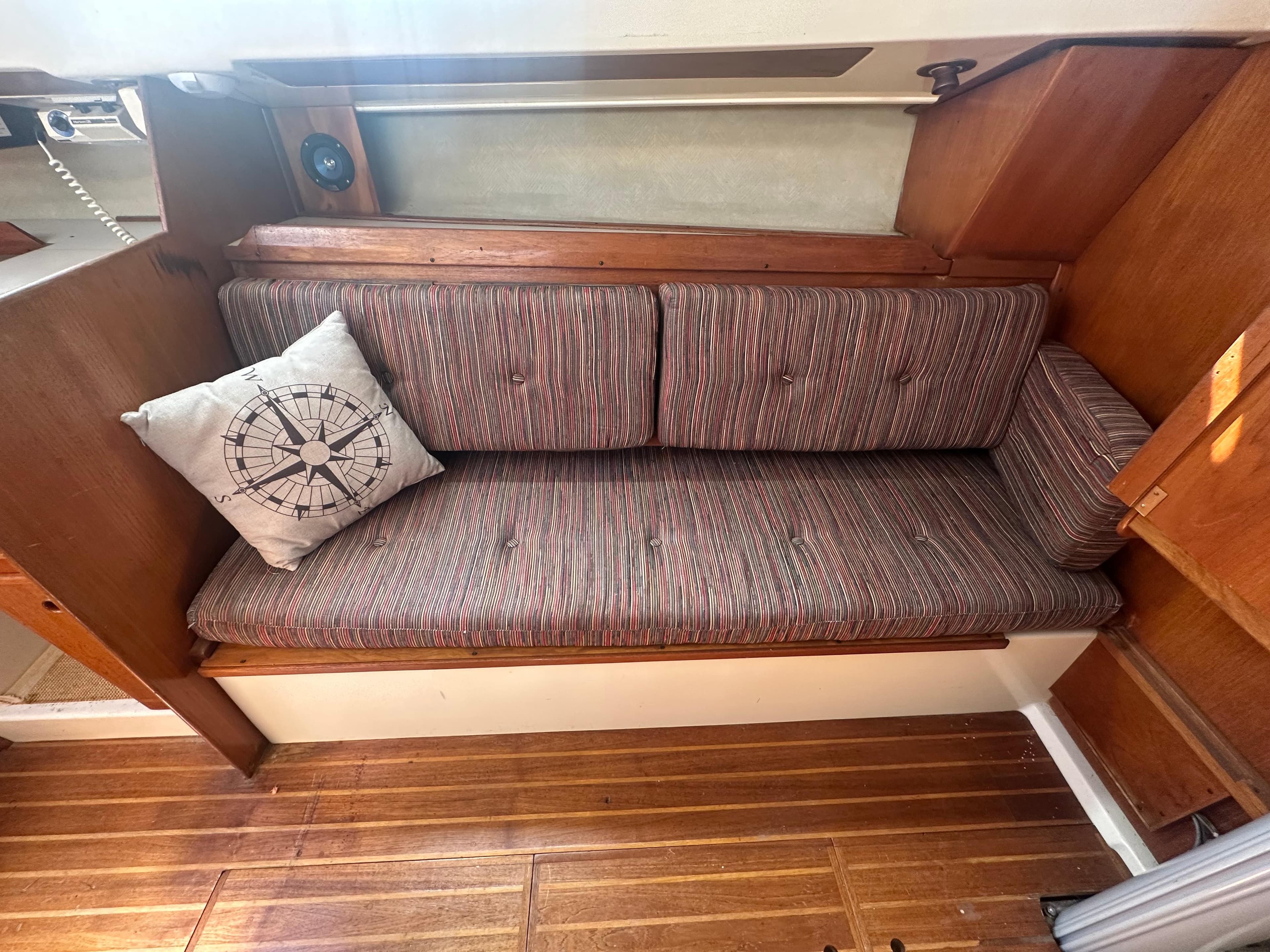 1981 Pearson 32 sailboat interior with cushioned seating and compass-themed pillow.