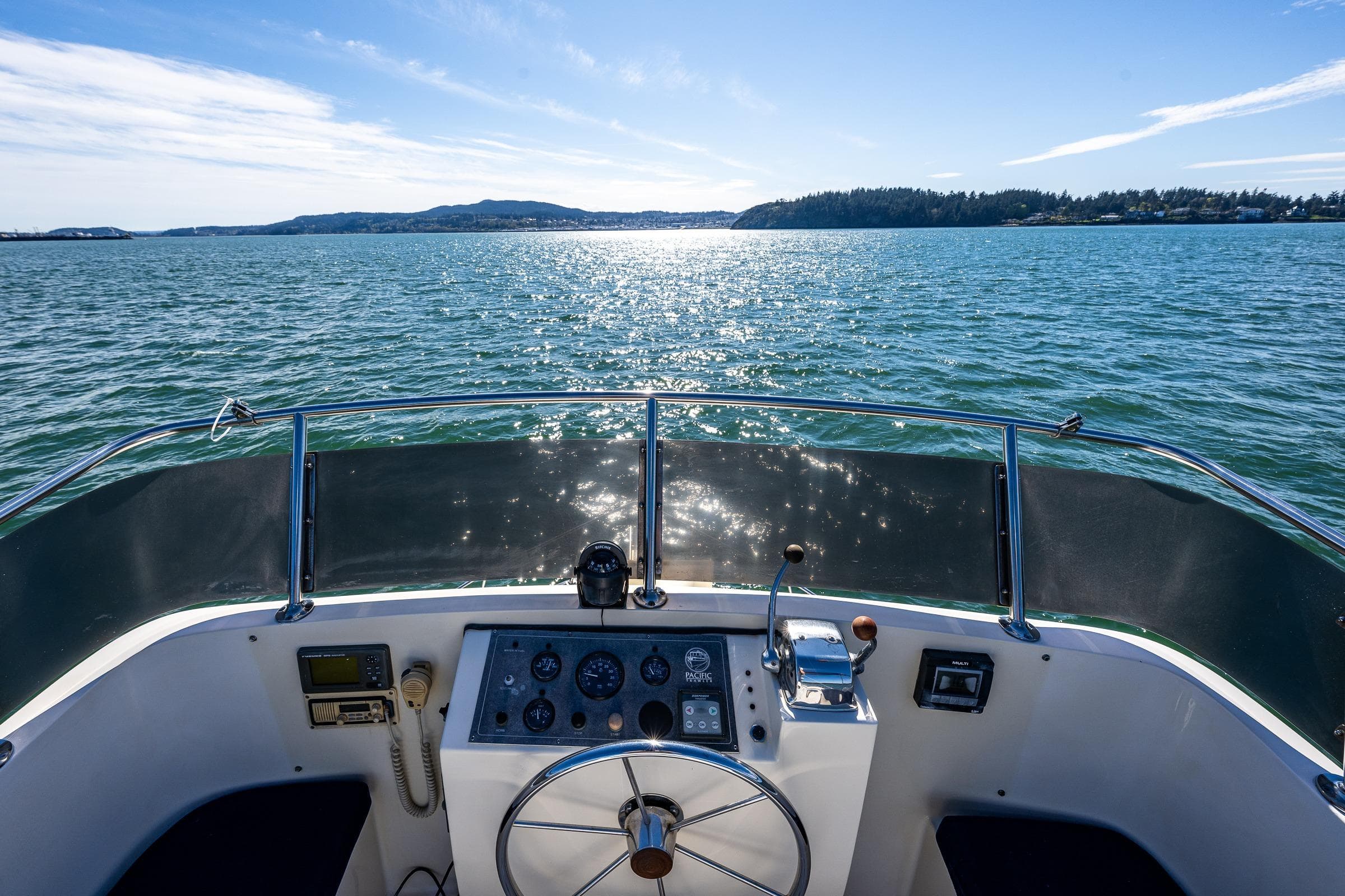 Cockpit view from a 1999 Pacific Trawler 40, overlooking serene waters and distant shoreline.