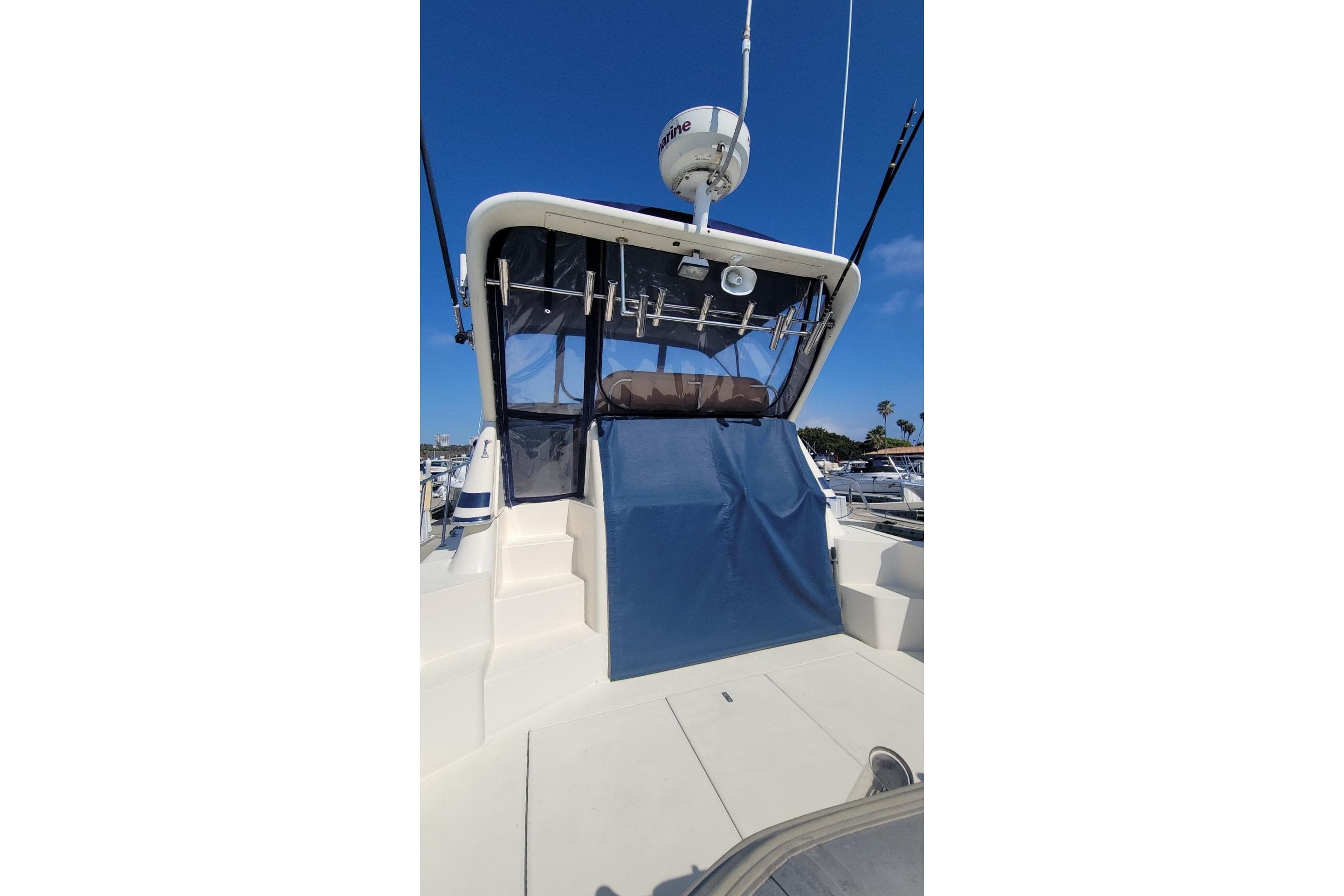 1989 Navigator 34 Flybridge yacht with blue canopy, docked under clear sky.