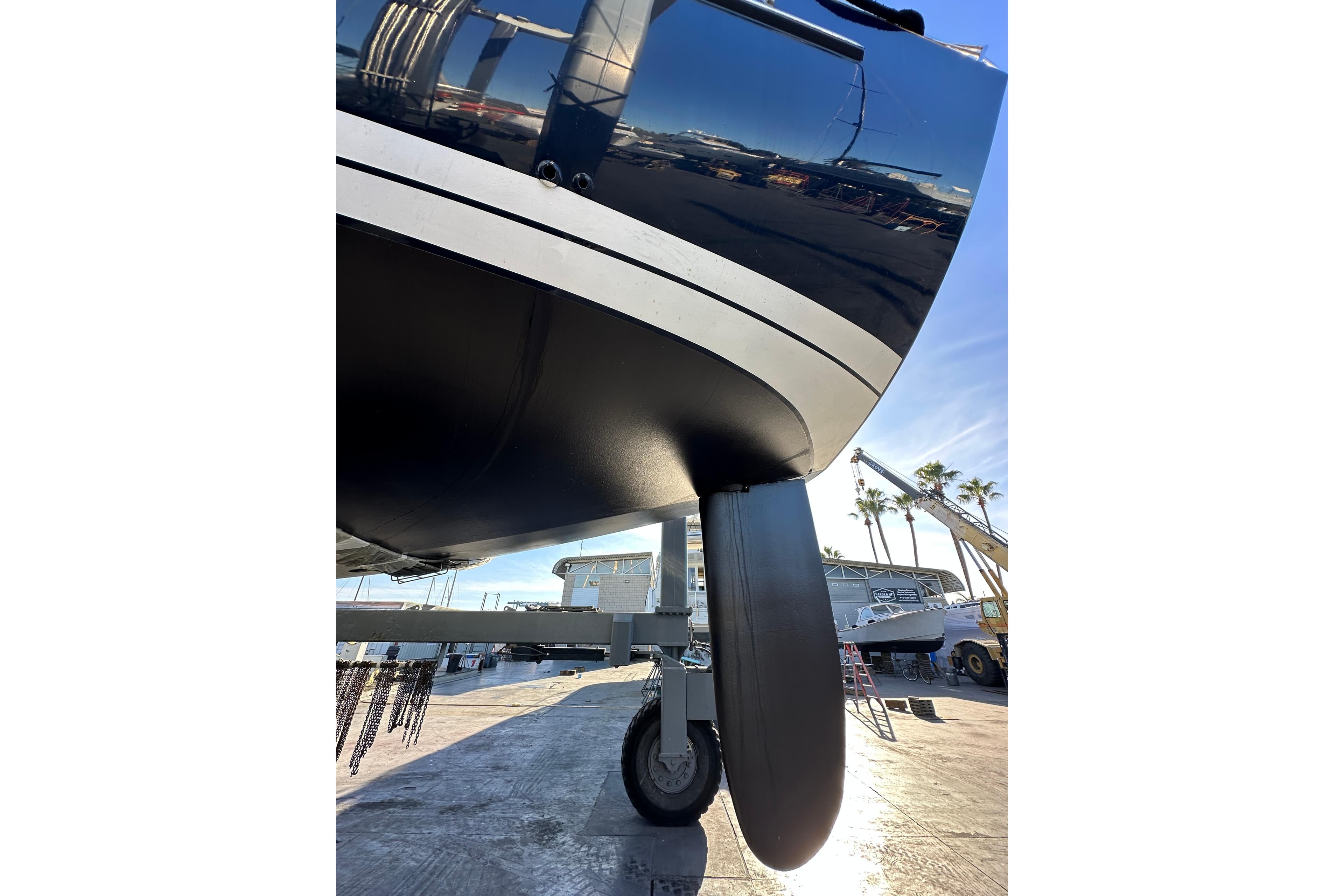2003 Beneteau 57 yacht hull and keel on a trailer in a marina.