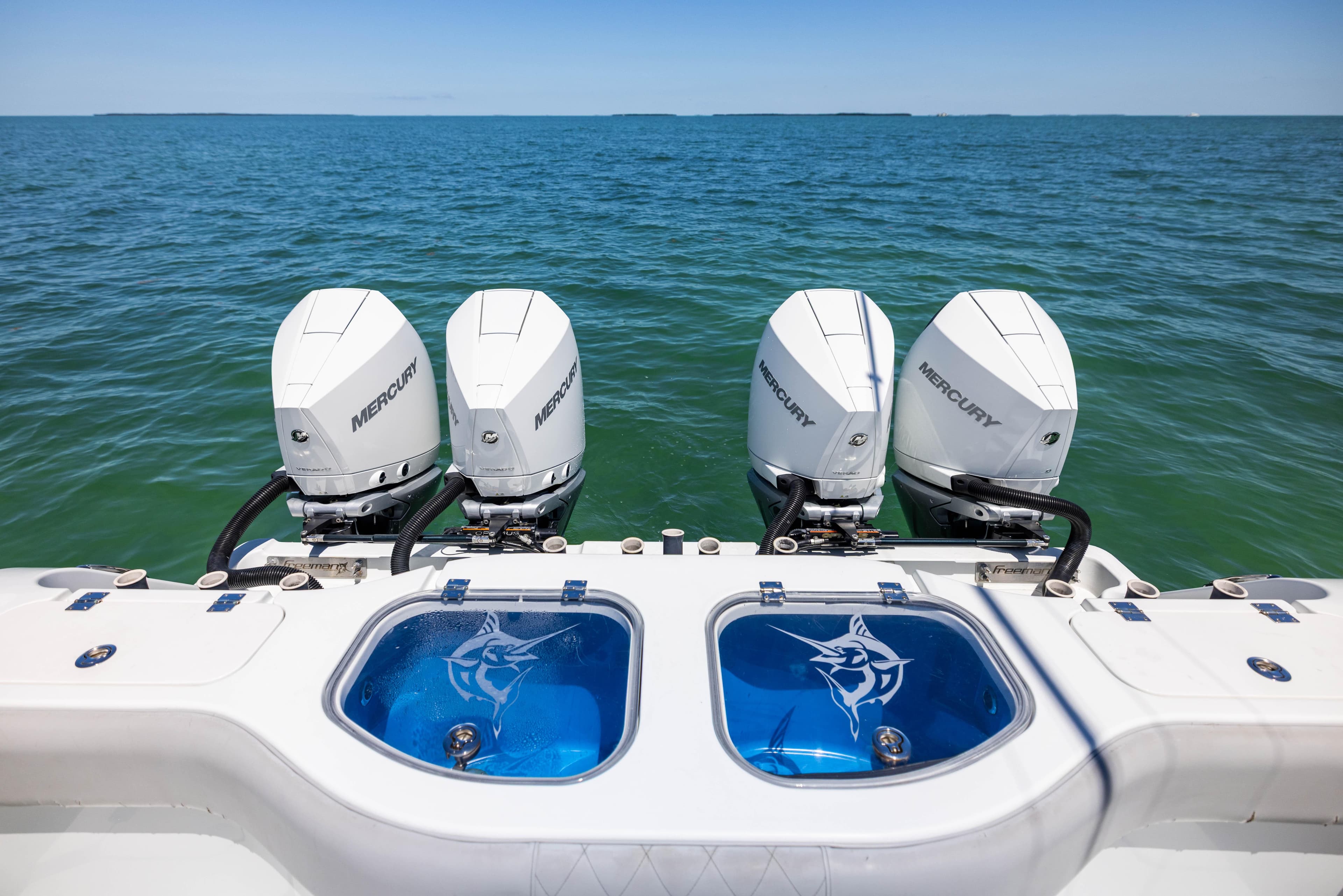 Four Mercury outboard engines on a 2021 Freeman 42 LR boat, ocean backdrop.