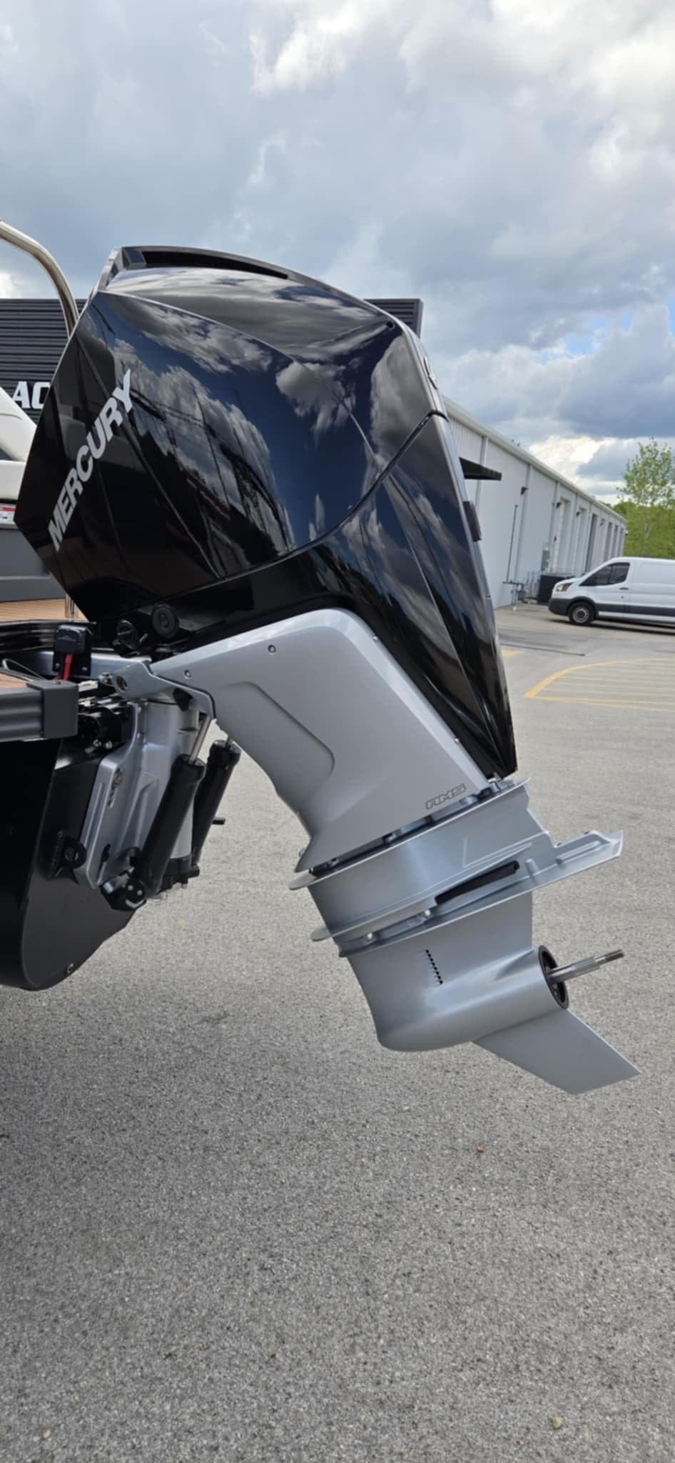 2025 Manitou Explore boat with Mercury outboard motor, parked outdoors.