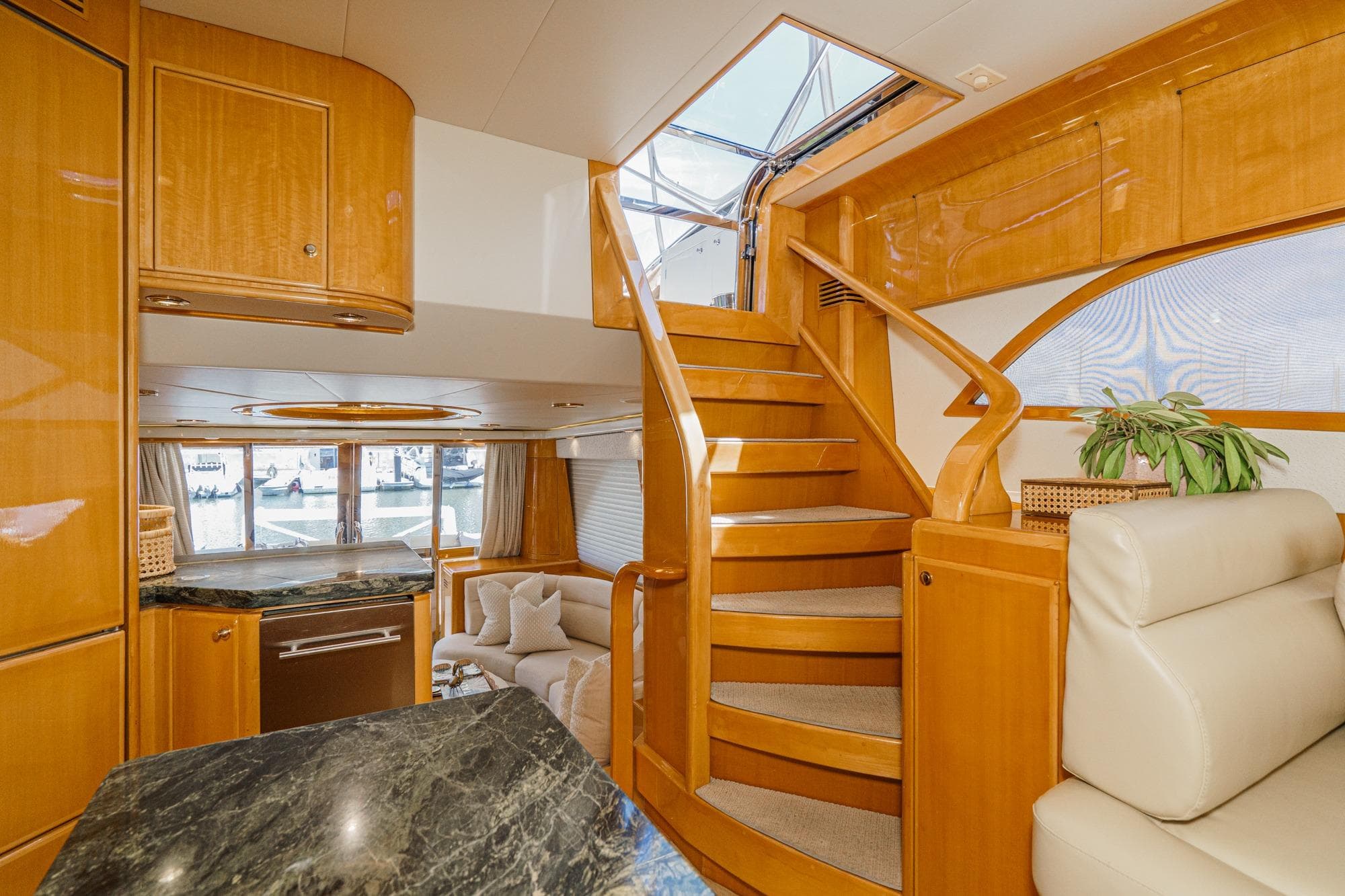 Luxurious interior of 2003 McKinna 65 Pilothouse yacht with elegant wood finishes and staircase.