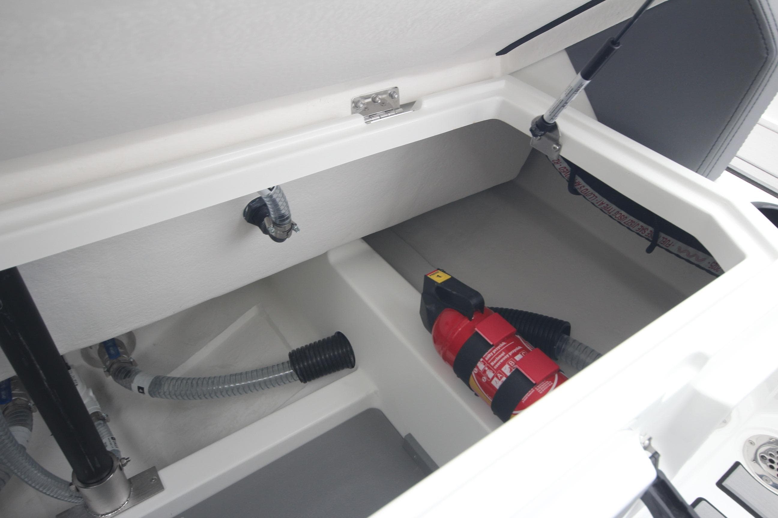 Storage compartment of Iron 767 boat, featuring a fire extinguisher and hoses, 2026 model.