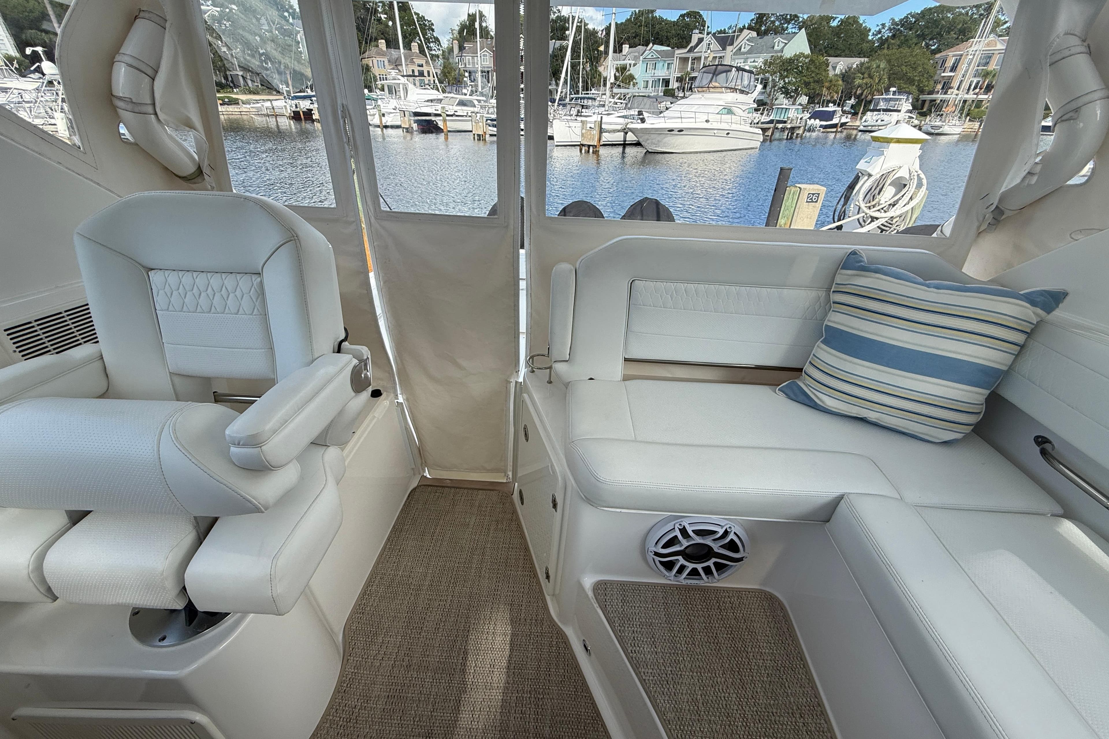 2023 Pursuit OS 355 Offshore interior with white seating, striped pillow, and marina view.
