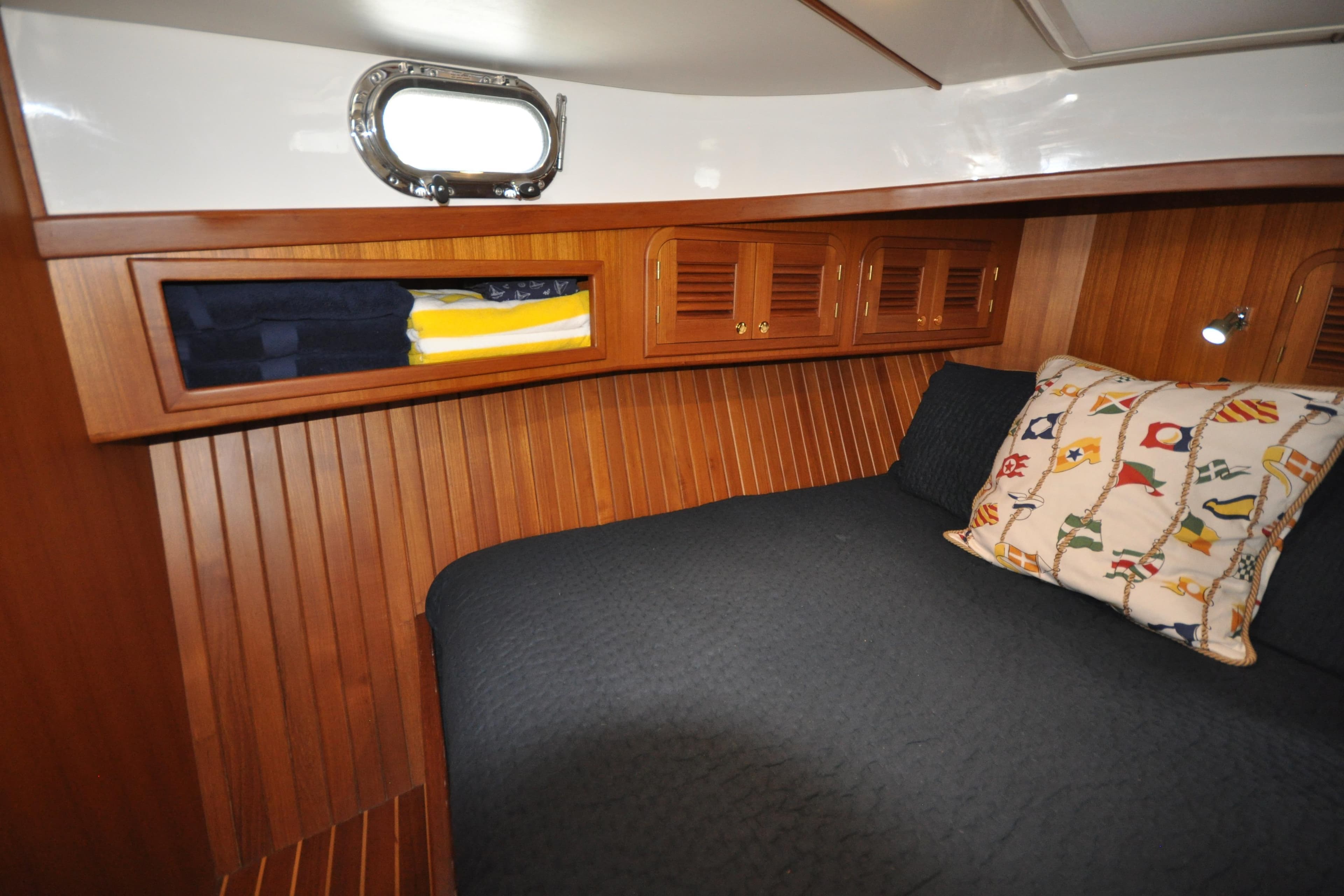 Cozy cabin interior of 2015 Helmsman Trawlers 31 Sedan with nautical-themed pillow.